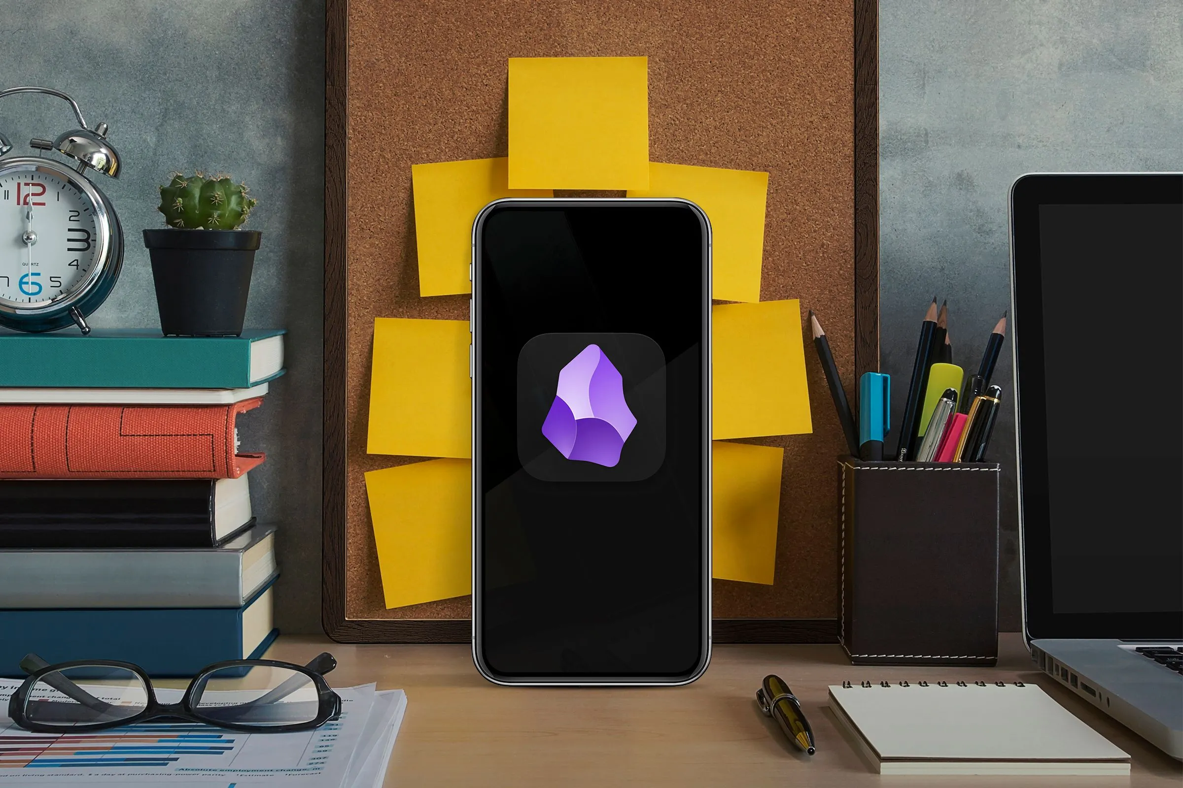 Điện thoại thông minh đang chạy ứng dụng ghi chú Obsidian trên bàn làm việc, tượng trưng cho giải pháp viết không xao nhãng.