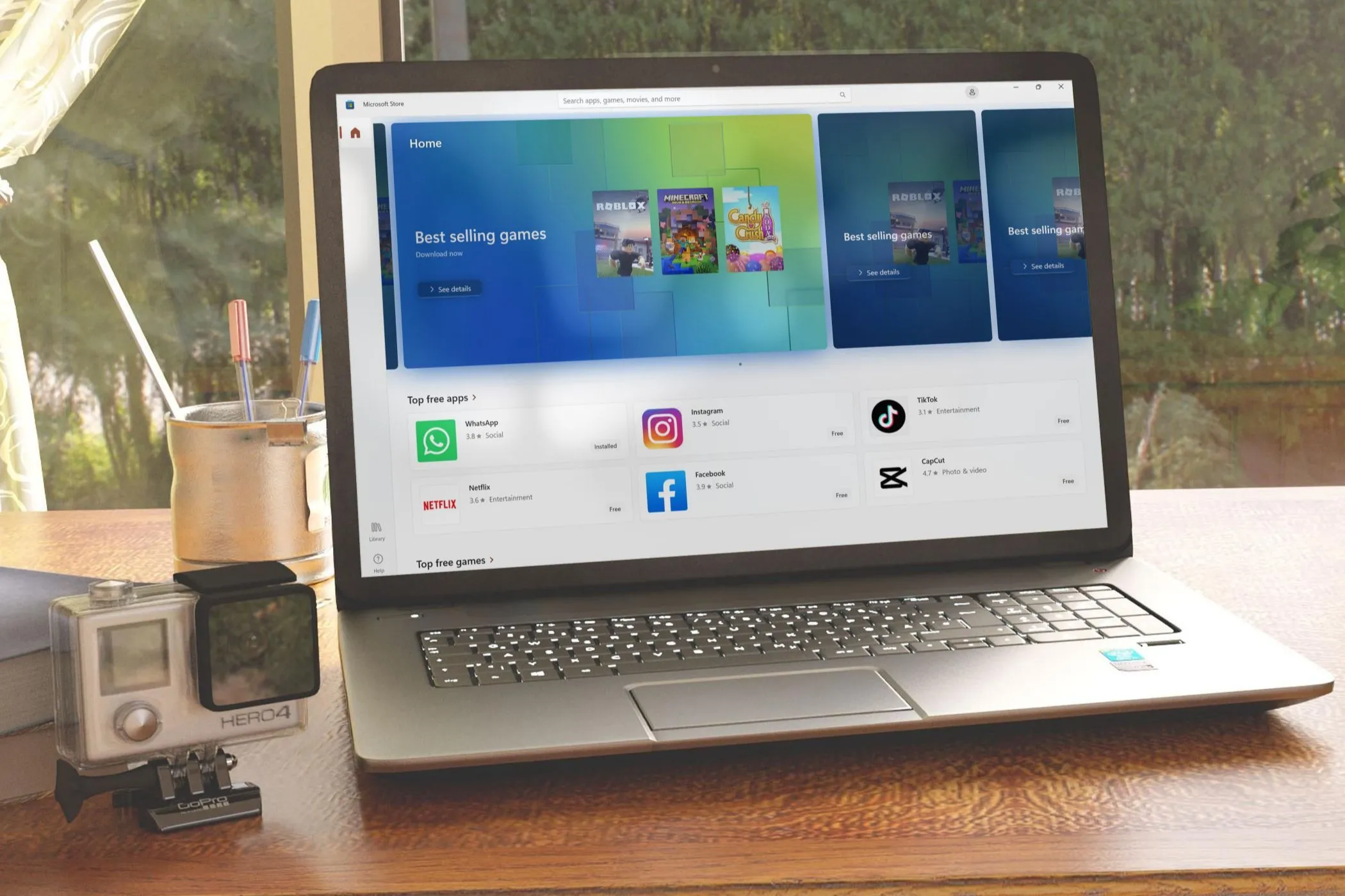 Giao diện Microsoft Store đang mở trên một chiếc laptop đặt trên bàn gần cửa sổ