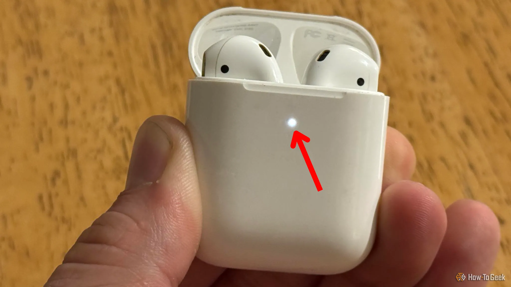 Hộp sạc AirPods mở nắp, đèn trạng thái nhấp nháy màu trắng báo hiệu chế độ ghép nối sẵn sàng.