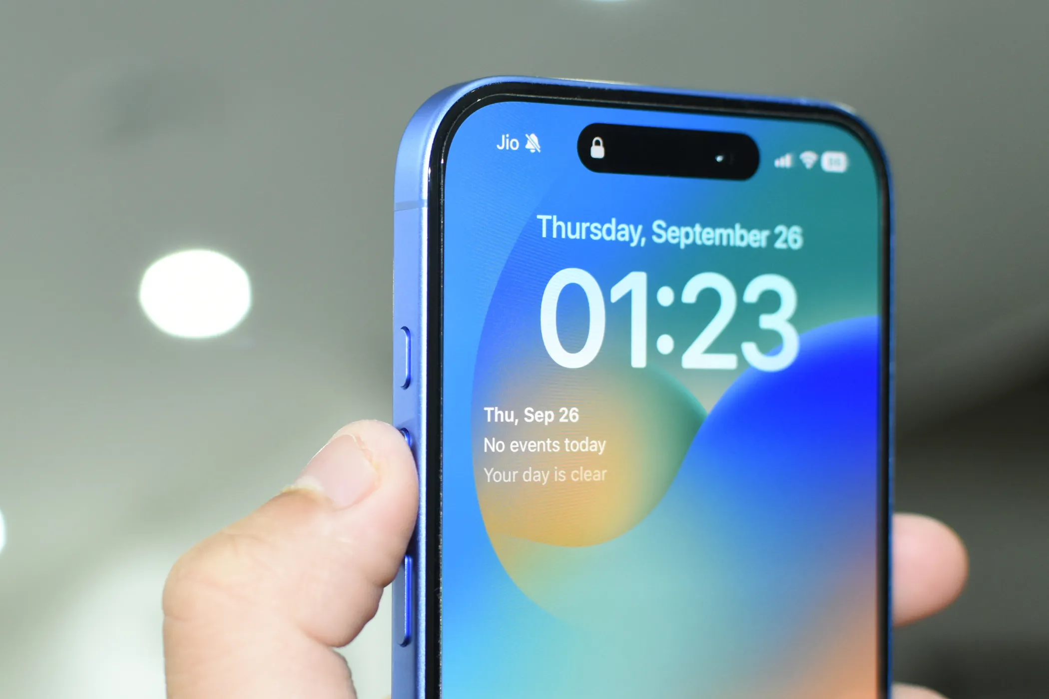iPhone 16 màu xanh Ultramarine với ngón tay chỉ vào Nút Tác Vụ (Action Button) ở cạnh bên.