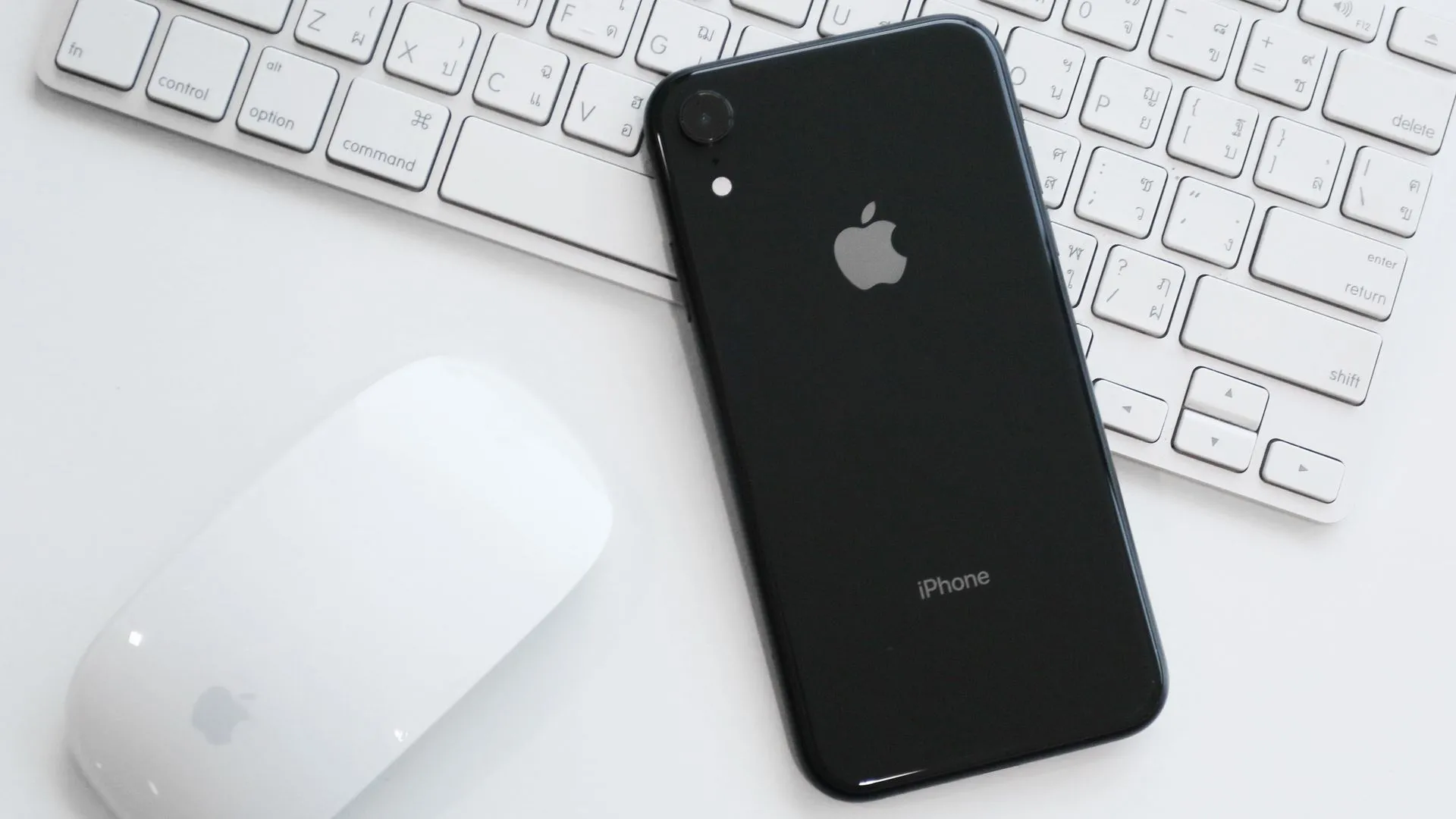 iPhone XR đặt trên bàn cùng Magic Mouse và Magic Keyboard, tượng trưng cho camera đơn nhưng chất lượng cao.