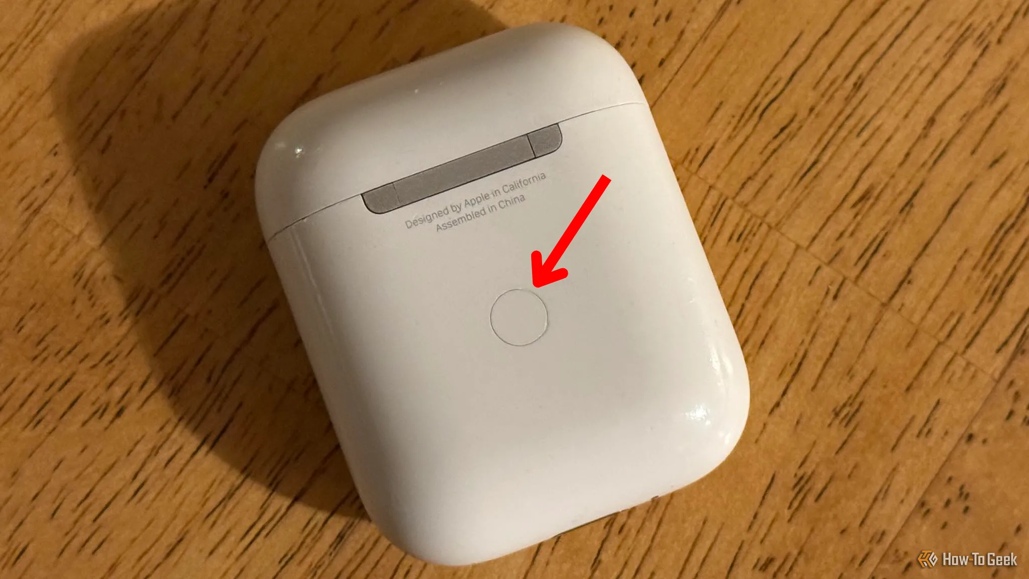 Mặt sau hộp sạc AirPods, mũi tên chỉ vào nút thiết lập để kích hoạt chế độ ghép nối.