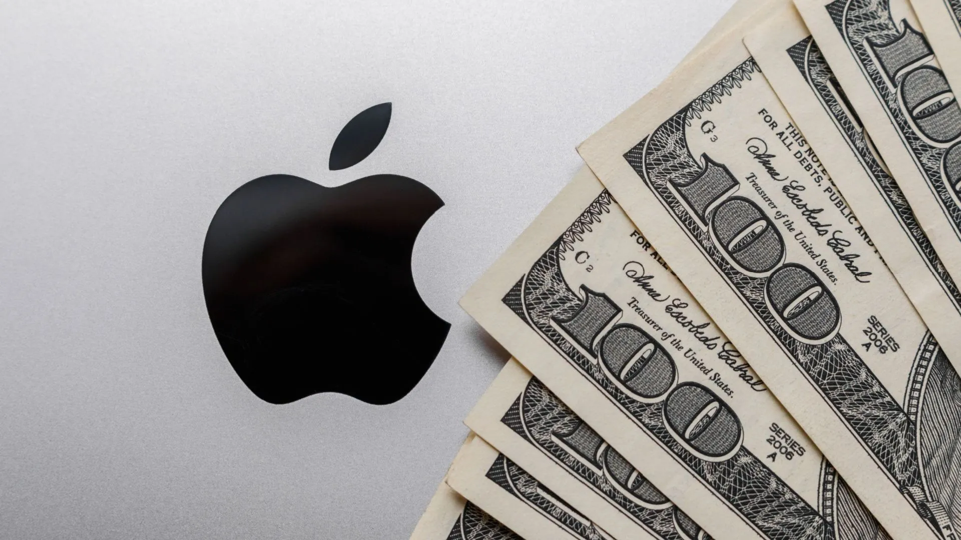 Máy tính MacBook với biểu tượng Apple và những tờ đô la trên bàn phím.