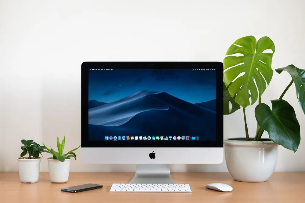Một chiếc iMac đời cũ đặt trên bàn làm việc gọn gàng, có thể chứa ổ cứng Fusion Drive hoặc HDD, gây ảnh hưởng đến tốc độ hoạt động.