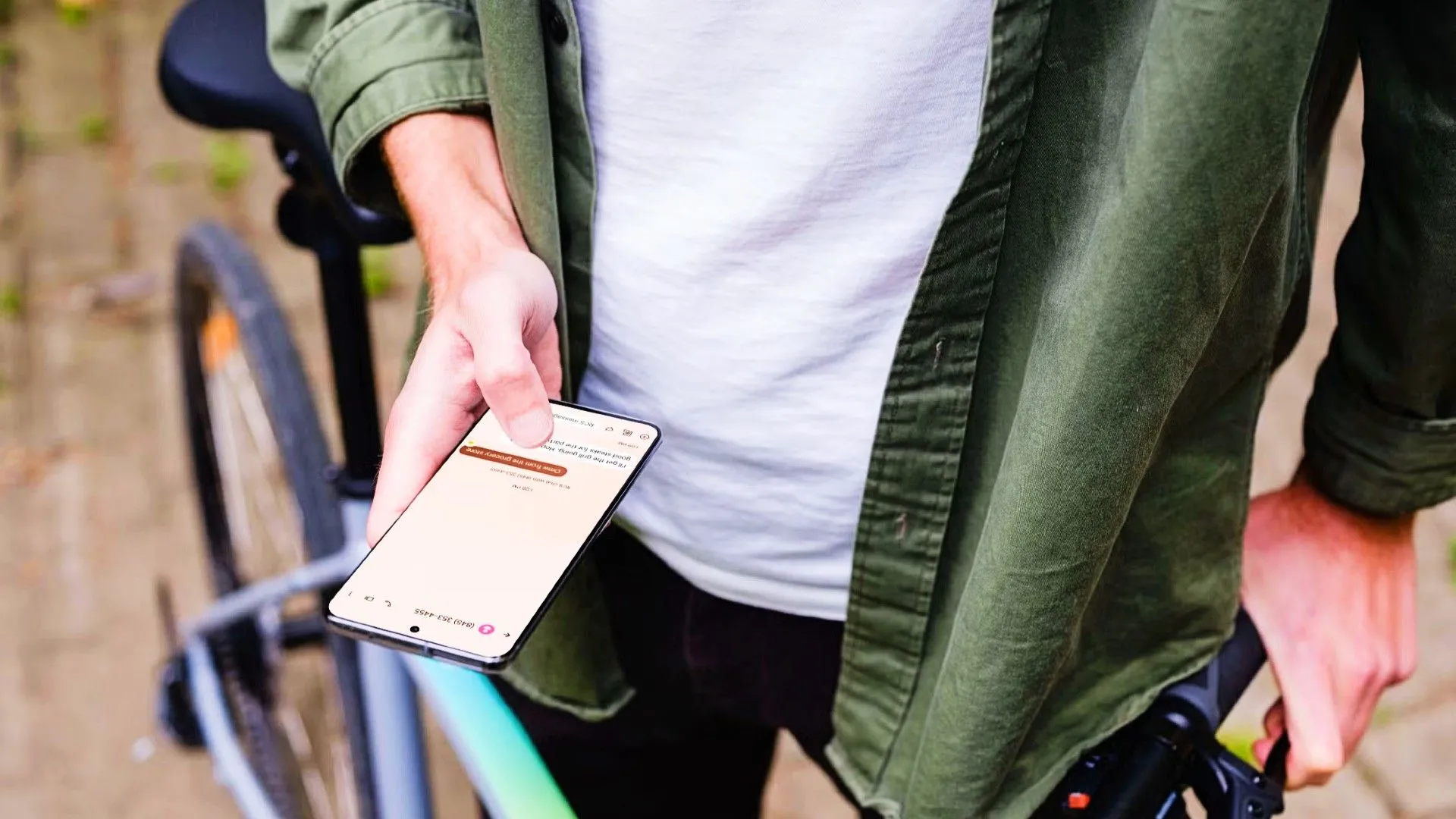 Một người đang cầm thiết bị Android cạnh xe đạp, có cuộc trò chuyện văn bản trên điện thoại