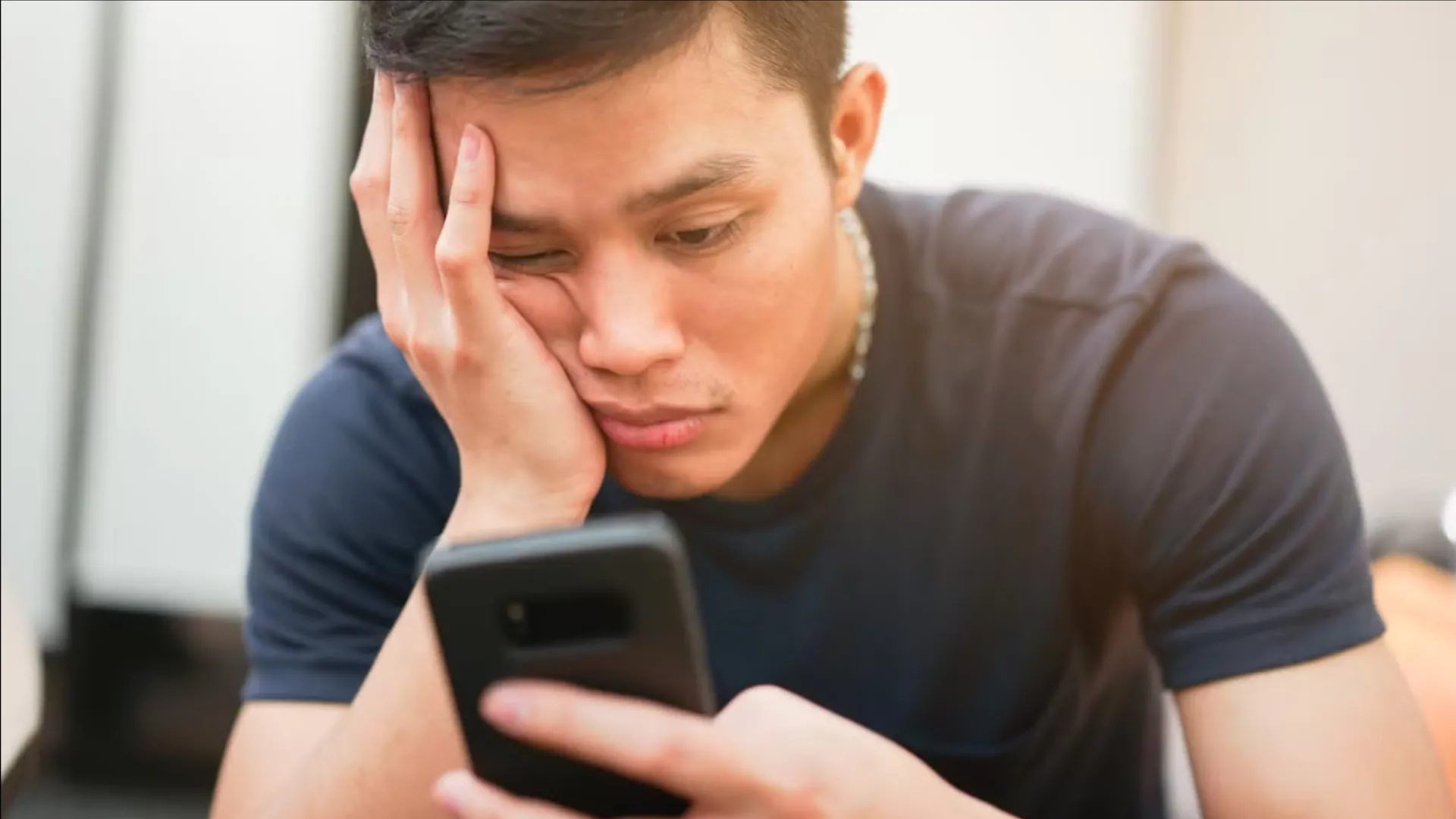 Một người dùng nhìn chằm chằm vào điện thoại với vẻ mặt buồn chán, minh họa hành vi lướt điện thoại vô thức (doomscrolling) cần được kiểm soát.