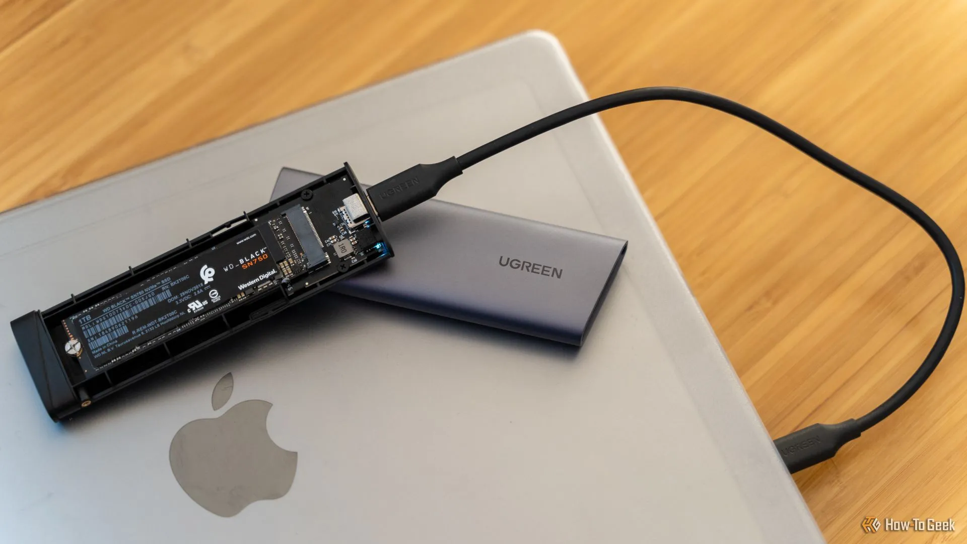 Một vỏ bọc SSD NVMe USB UGREEN cùng ổ SSD WD_BLACK SN750 bên trong, minh họa giải pháp nâng cấp lưu trữ cho các máy Mac cũ có ổ HDD chậm chạp.