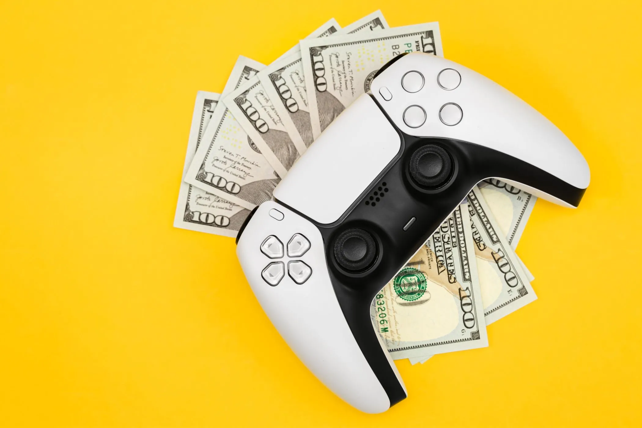Năm tờ tiền 100 đô la dưới tay cầm PS5, minh họa chi phí cao của việc mua các phiên bản game làm lại so với việc tận dụng mod miễn phí.