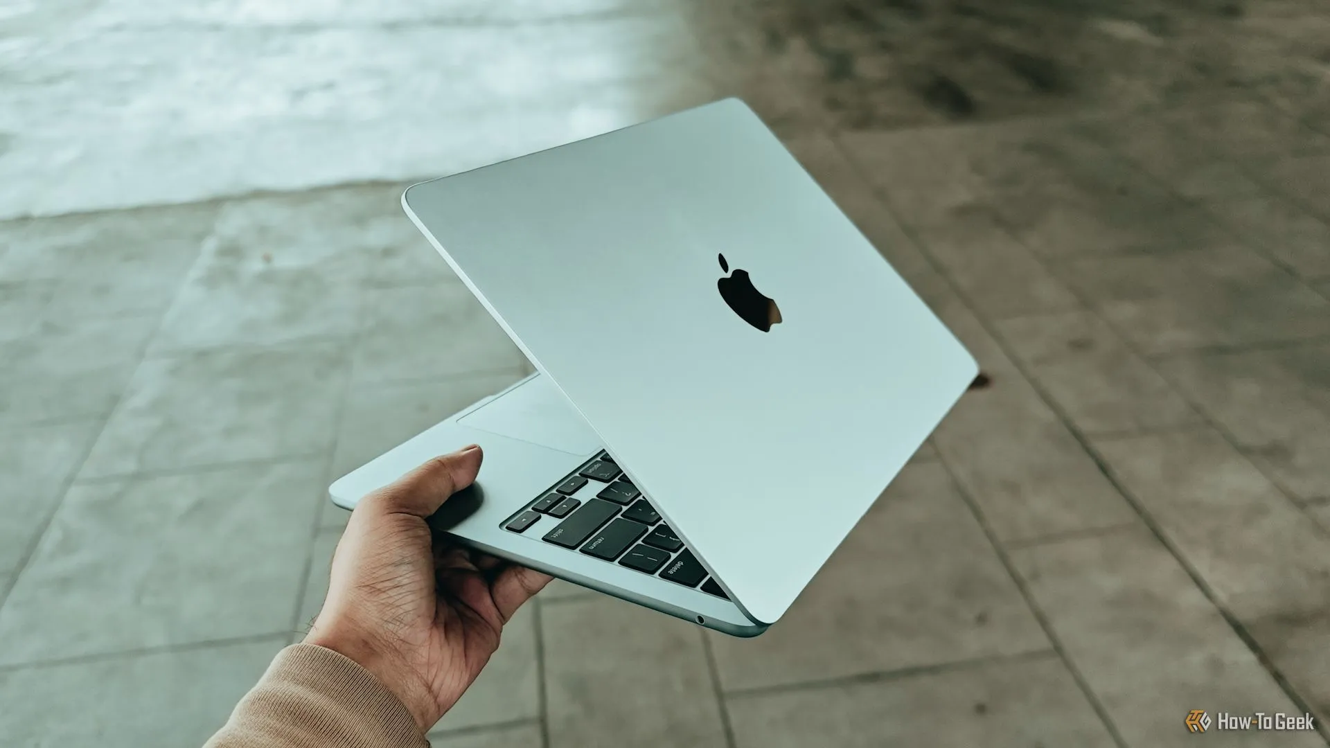 Người dùng cầm chiếc MacBook Air M4, thể hiện nhu cầu di động và kết nối mọi lúc mọi nơi