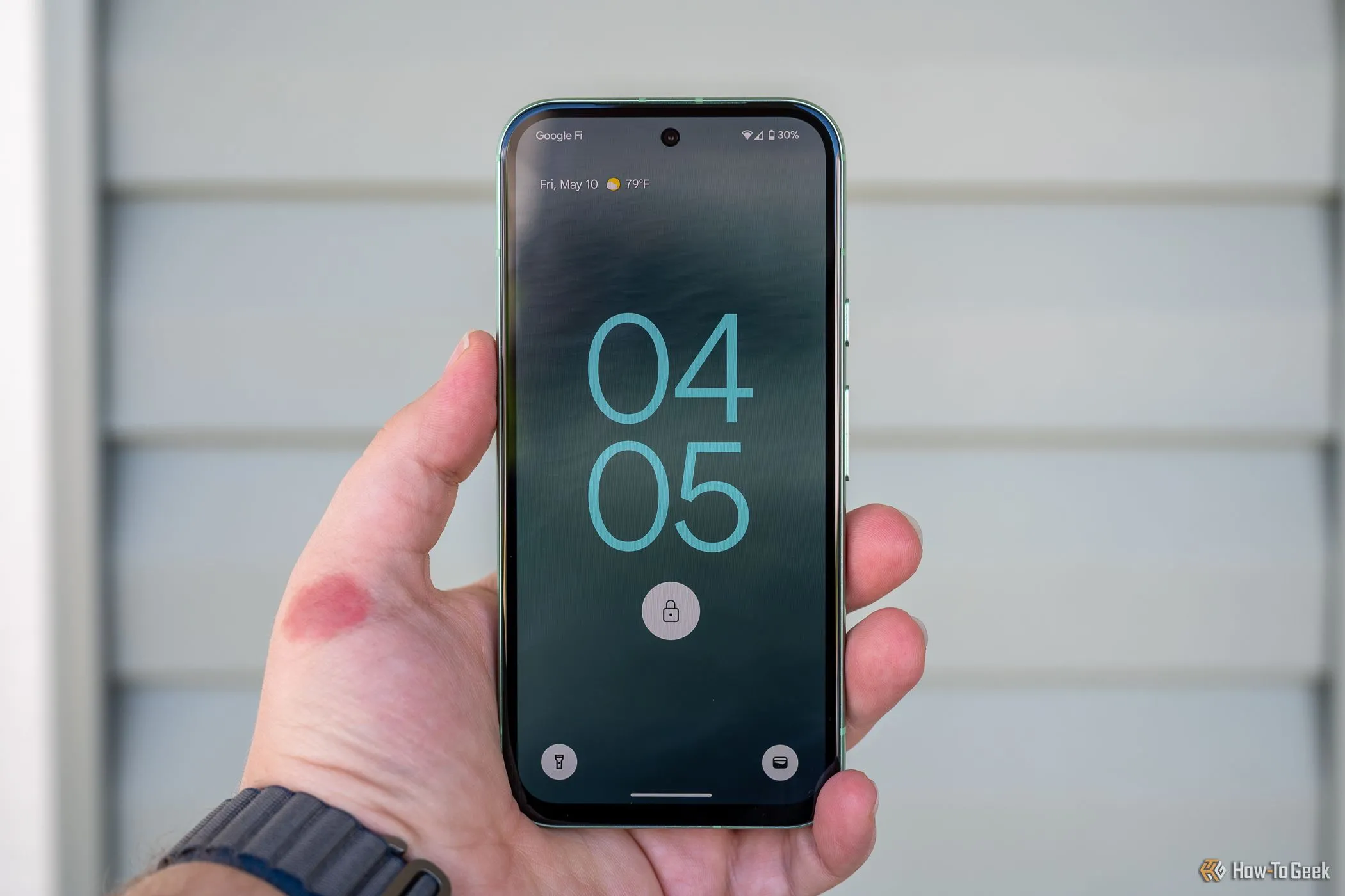 Người dùng đang cầm chiếc Google Pixel 8a hiển thị màn hình khóa, minh họa trạng thái yêu cầu nhập mã PIN hoặc mật khẩu sau khi điện thoại Android tự động khởi động lại.