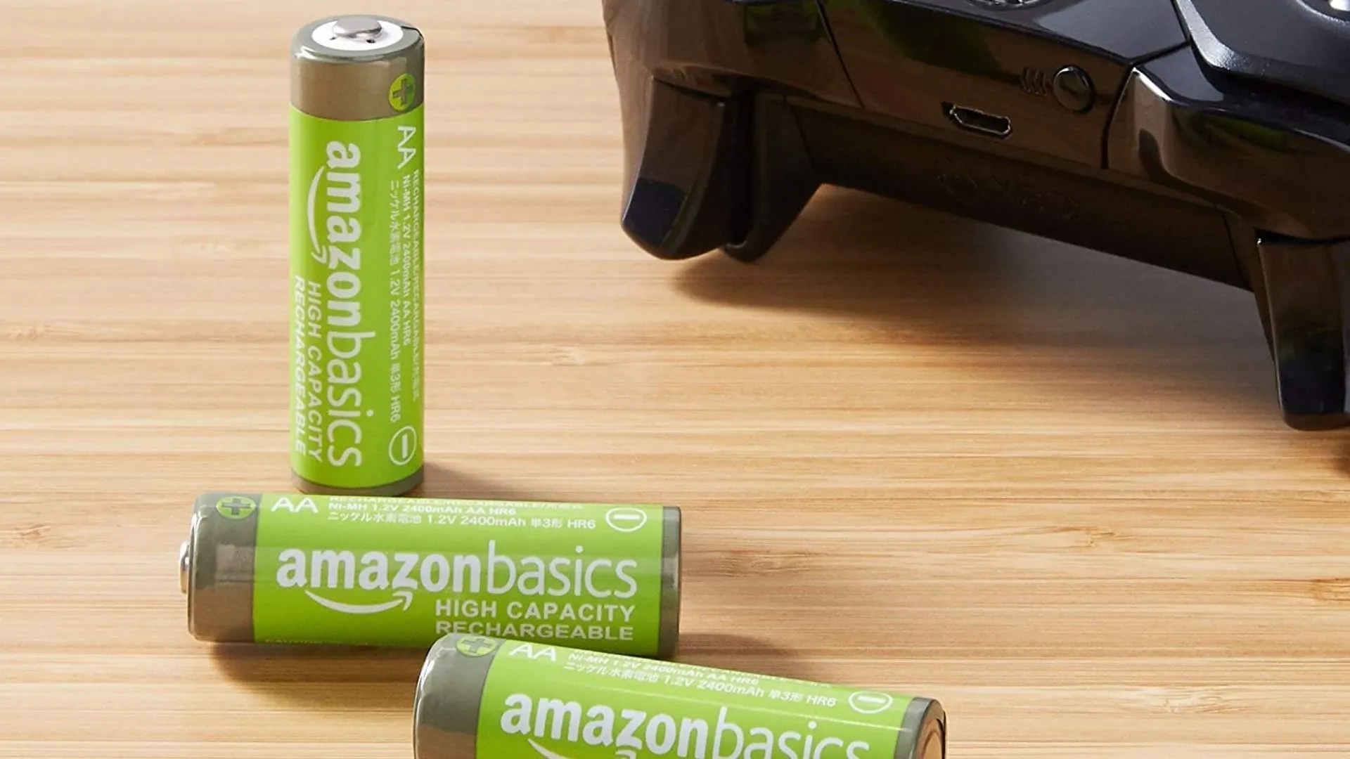 Pin AA sạc AmazonBasics trên bàn gỗ cạnh tay cầm Xbox