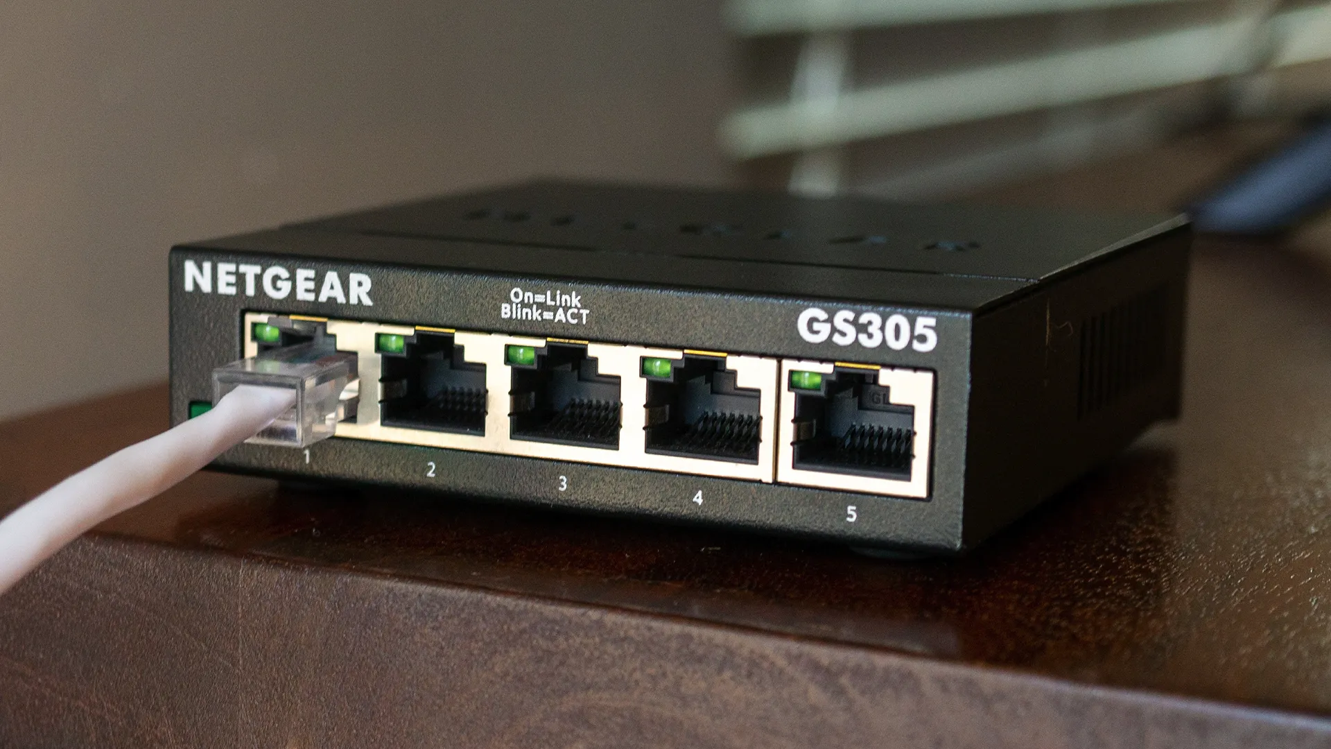 Switch mạng Netgear 5 cổng được kết nối cáp Ethernet, minh họa tốc độ Gigabit.