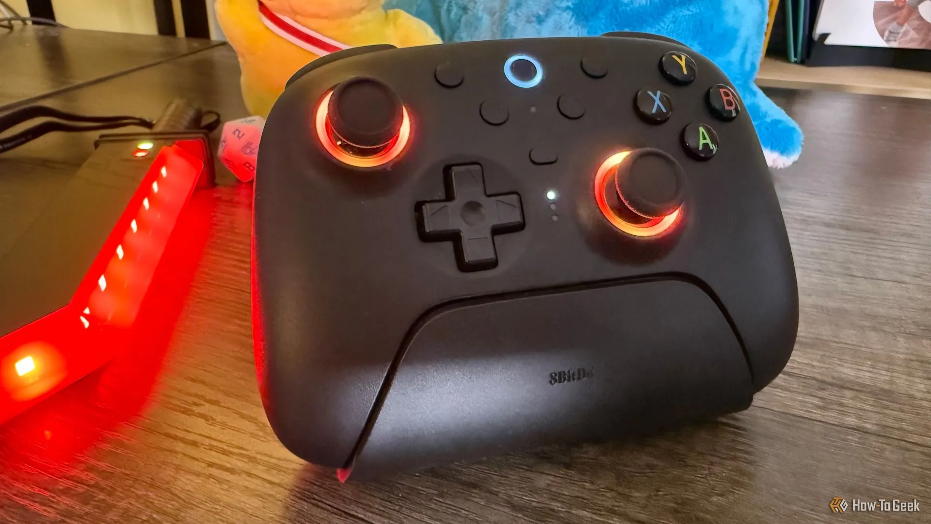 Tay cầm 8BitDo Ultimate 2 Wireless Controller với vòng đèn LED màu đỏ phát sáng quanh cần điều khiển.