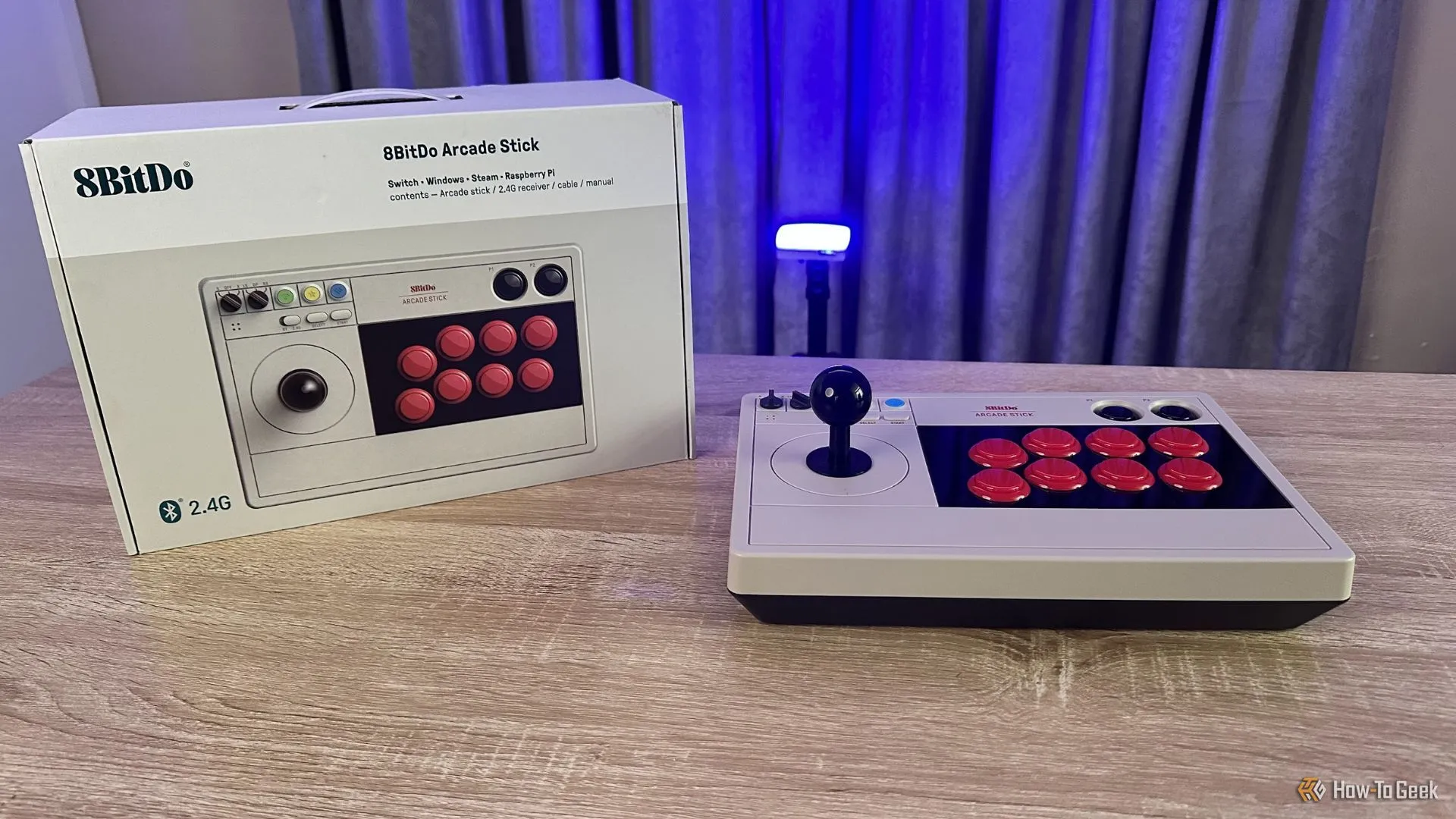 Tay cầm arcade 8BitDo cho Switch màu đen được đặt cạnh hộp bán lẻ của nó, thể hiện thiết kế của sản phẩm.