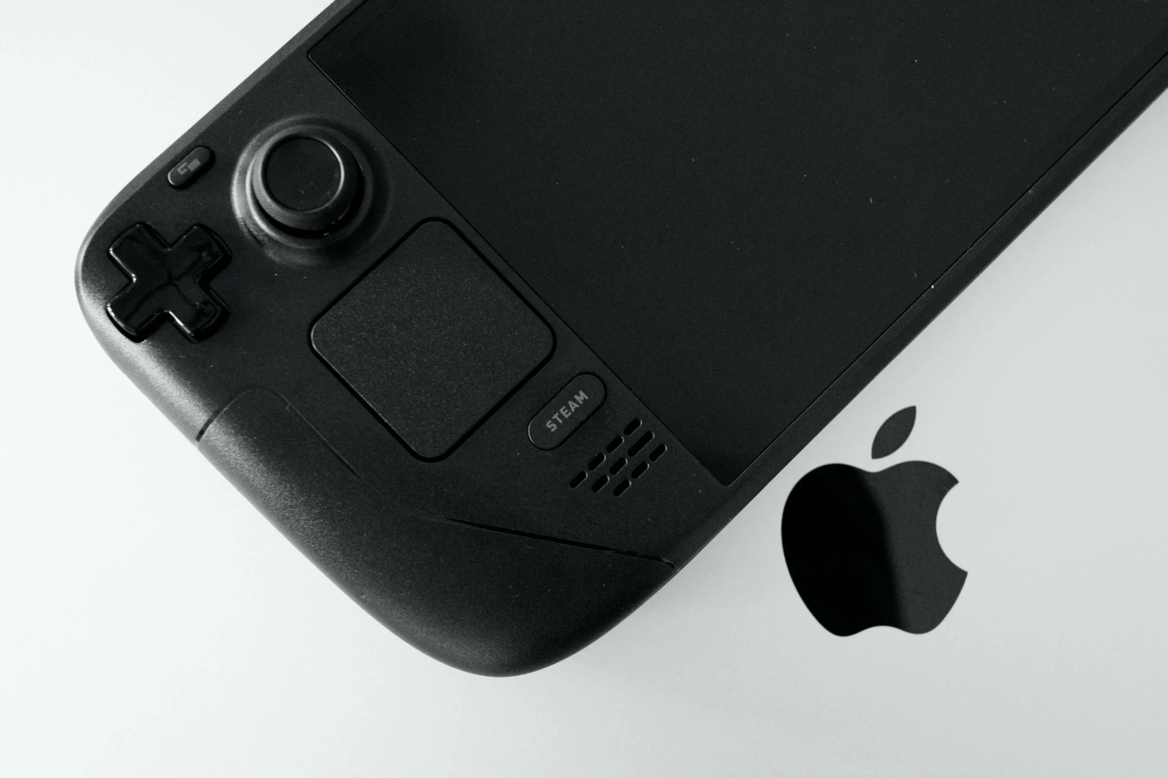 Thiết bị chơi game Steam Deck OLED đặt trên bàn phím MacBook Pro, minh họa khả năng kết nối và điều khiển Steam Deck từ máy tính.