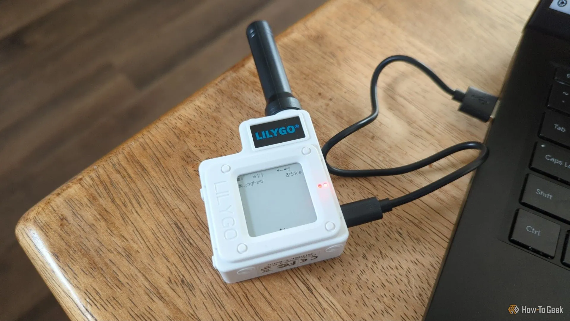 Thiết bị radio Lilygo T-Echo LoRa được kết nối với laptop trên bàn, thể hiện sự nhỏ gọn và tính tiện dụng của nó trong việc thiết lập mạng lưới Meshtastic.