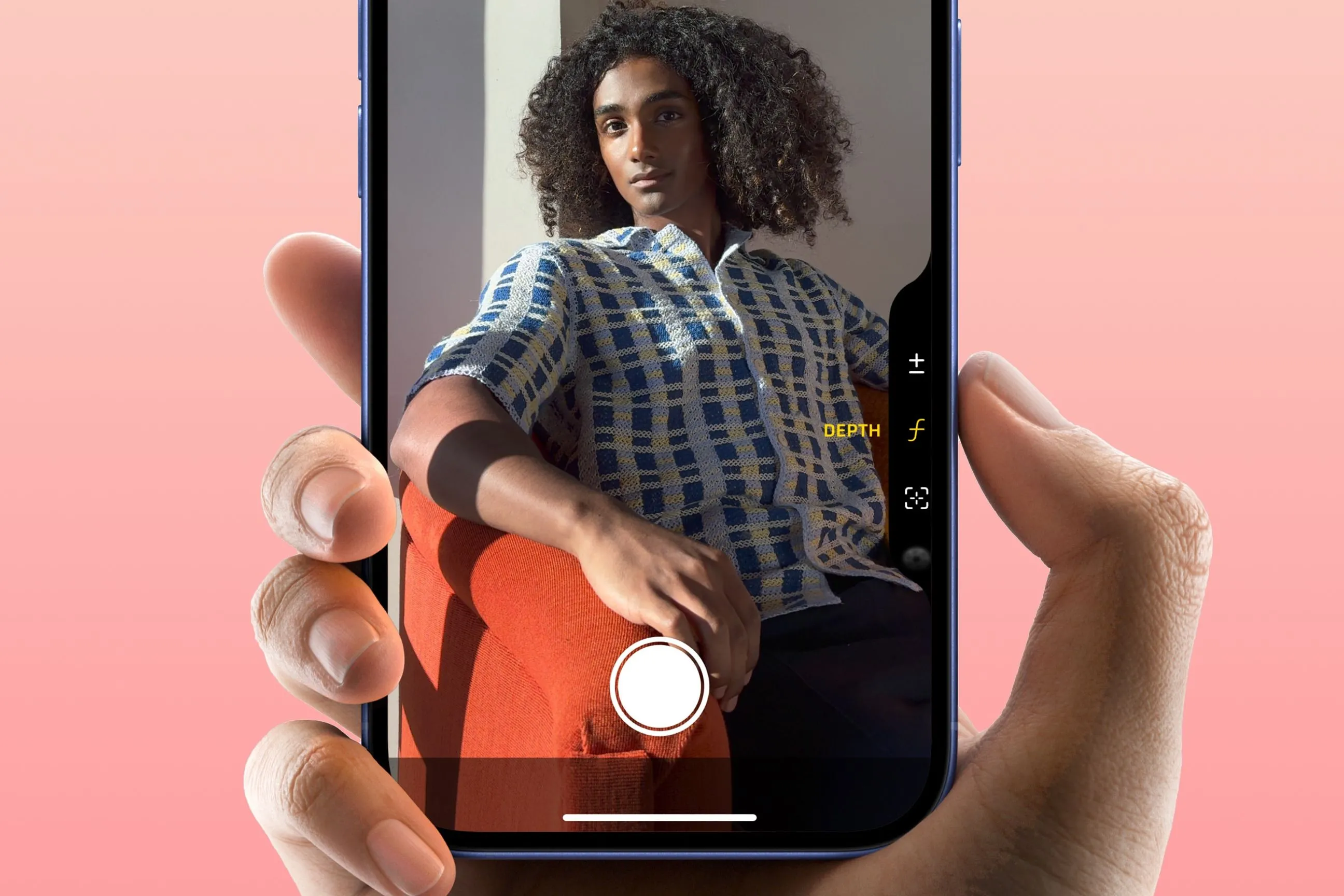 Bàn tay đang giữ iPhone 16 với ngón trỏ nhấn nút chụp Camera Control