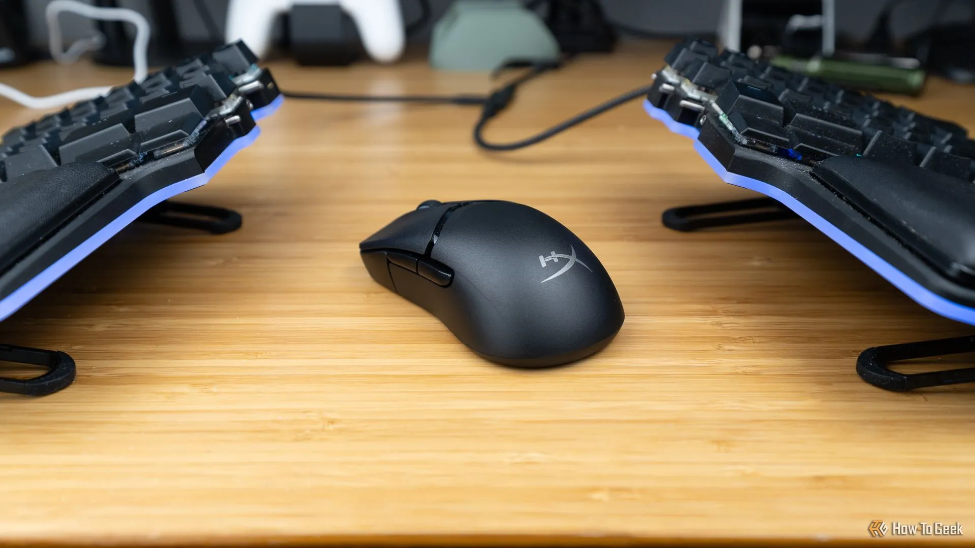 Chuột gaming không dây HyperX Pulsefire Saga Pro đặt giữa hai nửa bàn phím