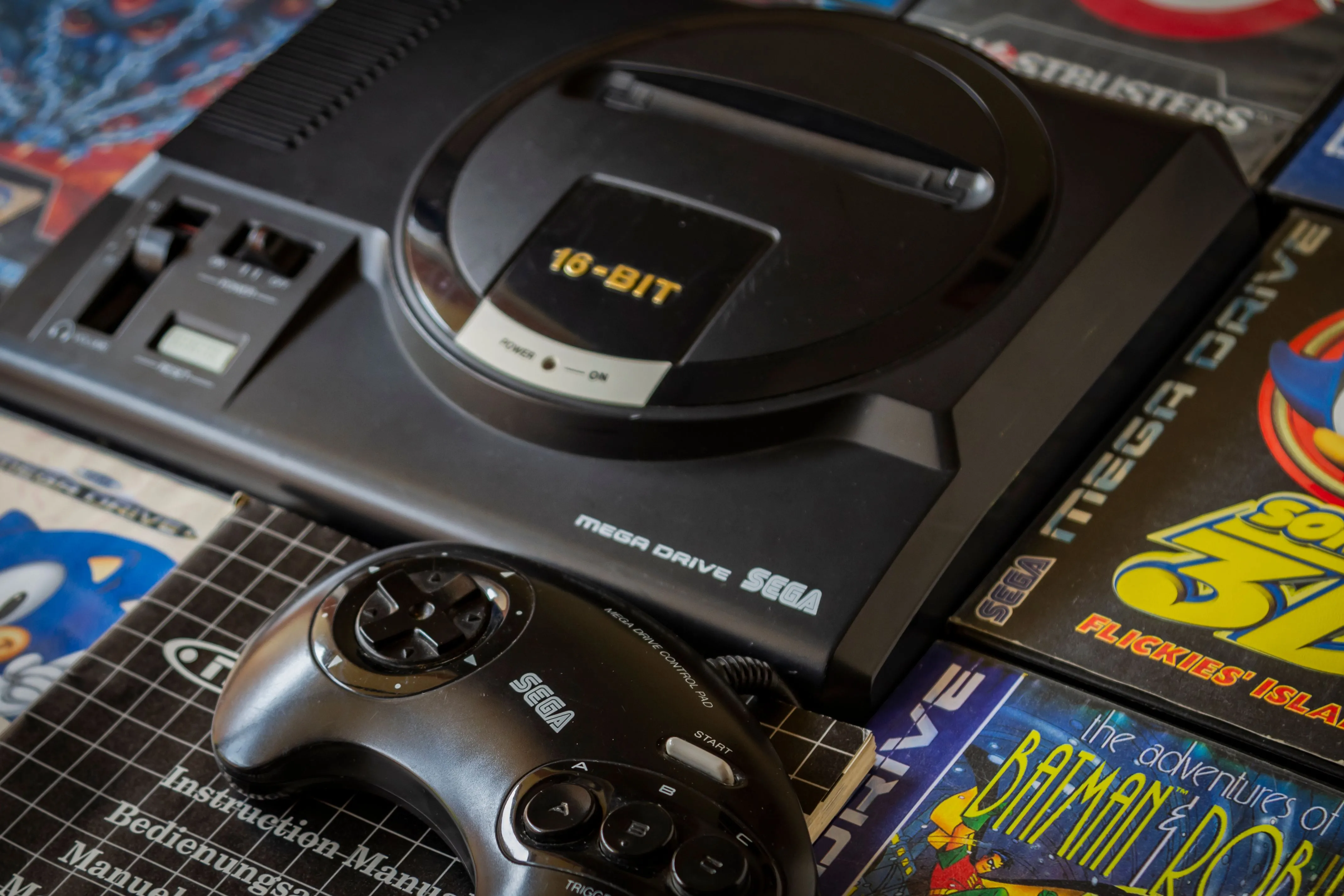 Console Sega Genesis màu đen cùng một số băng game và tay cầm, biểu tượng của 'Blast Processing'