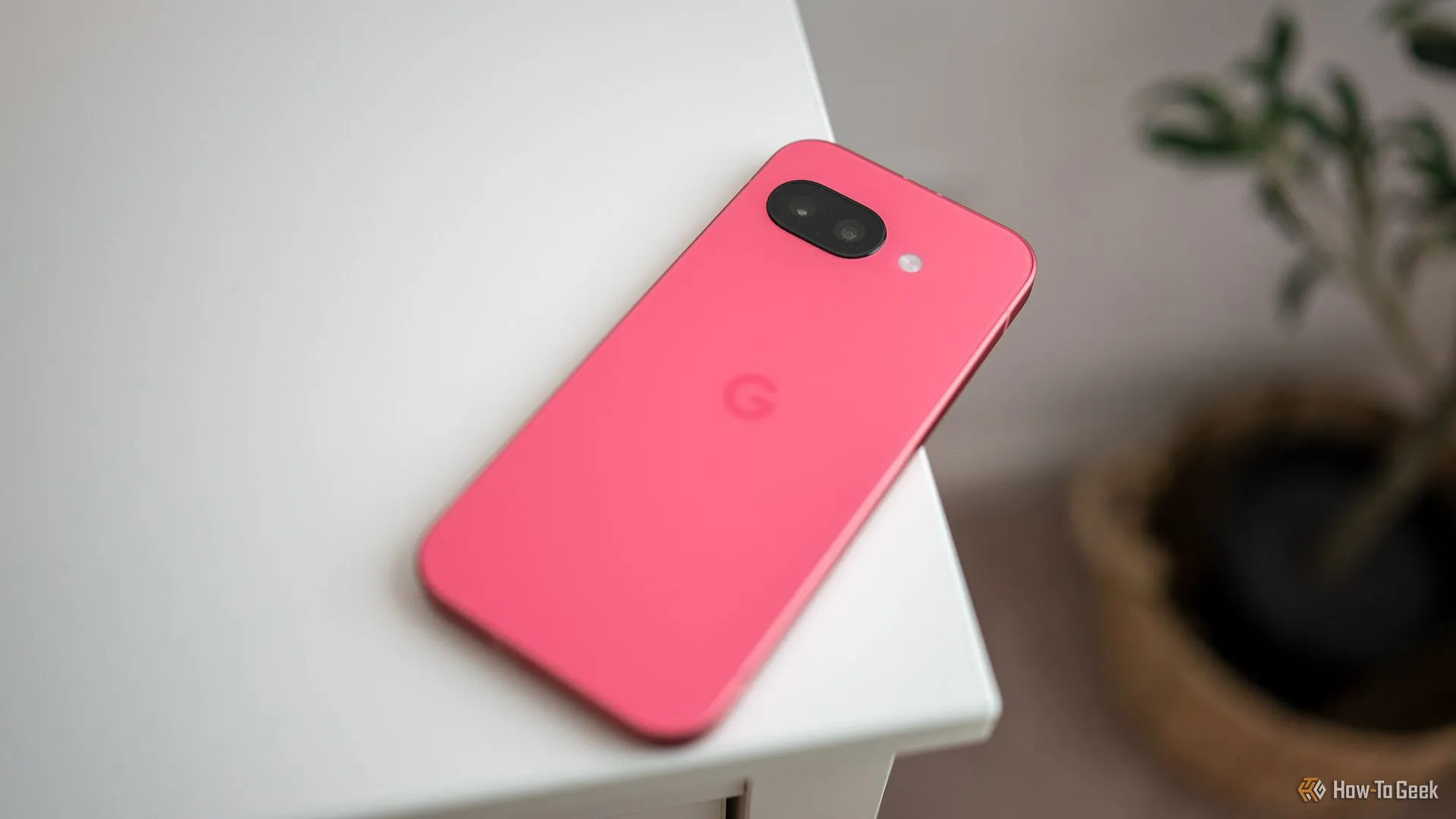 Điện thoại Google Pixel 9a đặt trên mặt bàn màu gỗ, hiển thị màn hình khóa