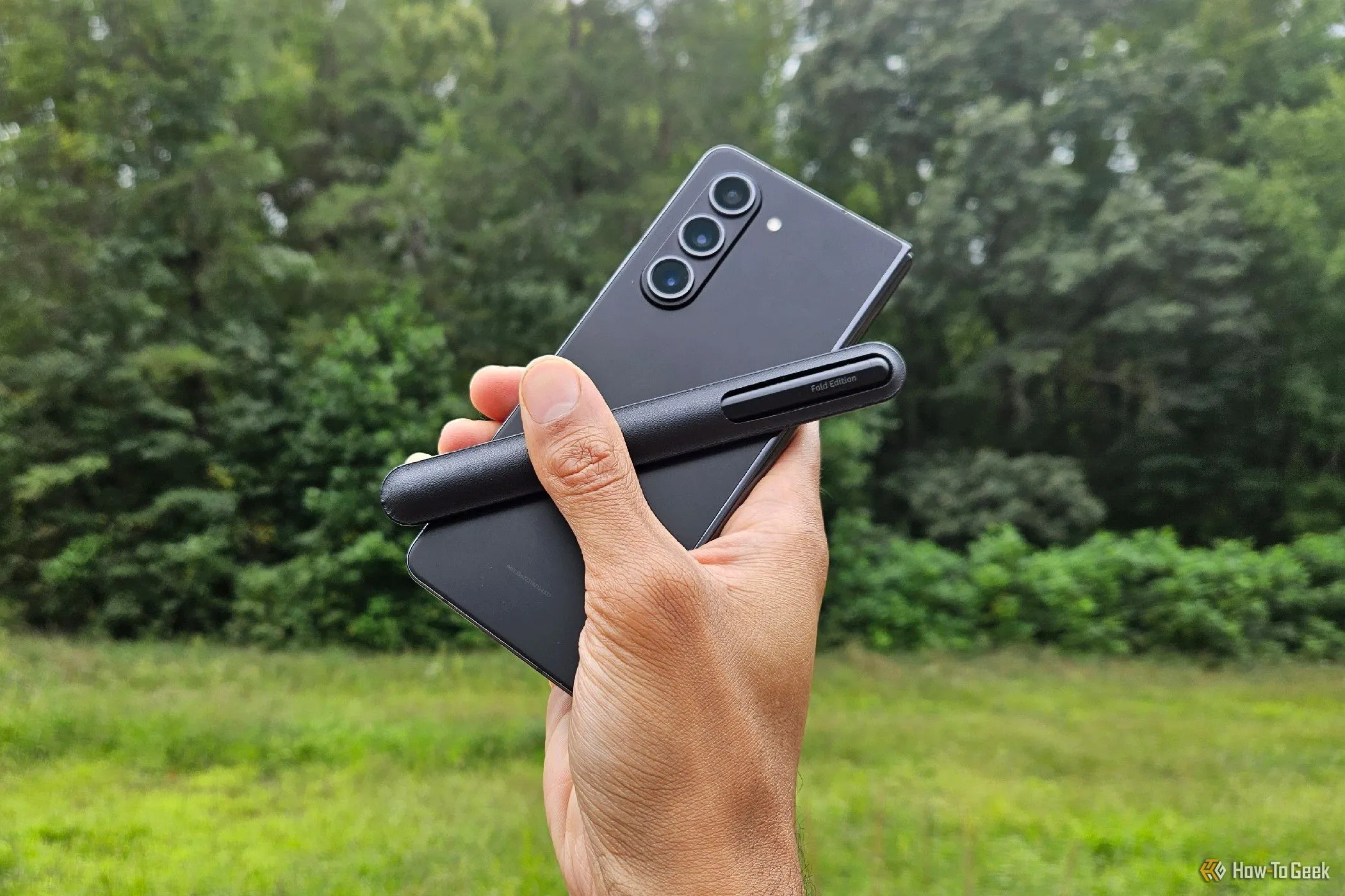 Điện thoại Samsung Galaxy Z Fold 5 với Bút S Pen Fold Edition đặt bên cạnh, trên nền bàn làm việc gỗ