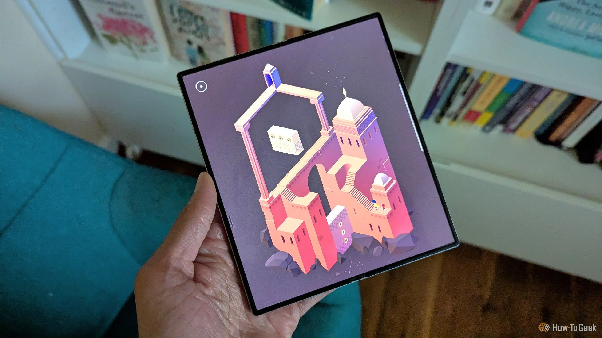 Game Monument Valley 2 đang hiển thị trên Galaxy Z Fold 6 với bối cảnh sách ở hậu cảnh.