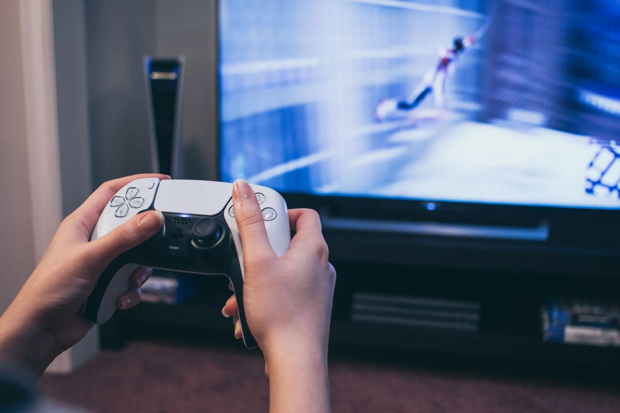 Giữ tay cầm DualSense PS5 trước TV hiển thị Spider-Man