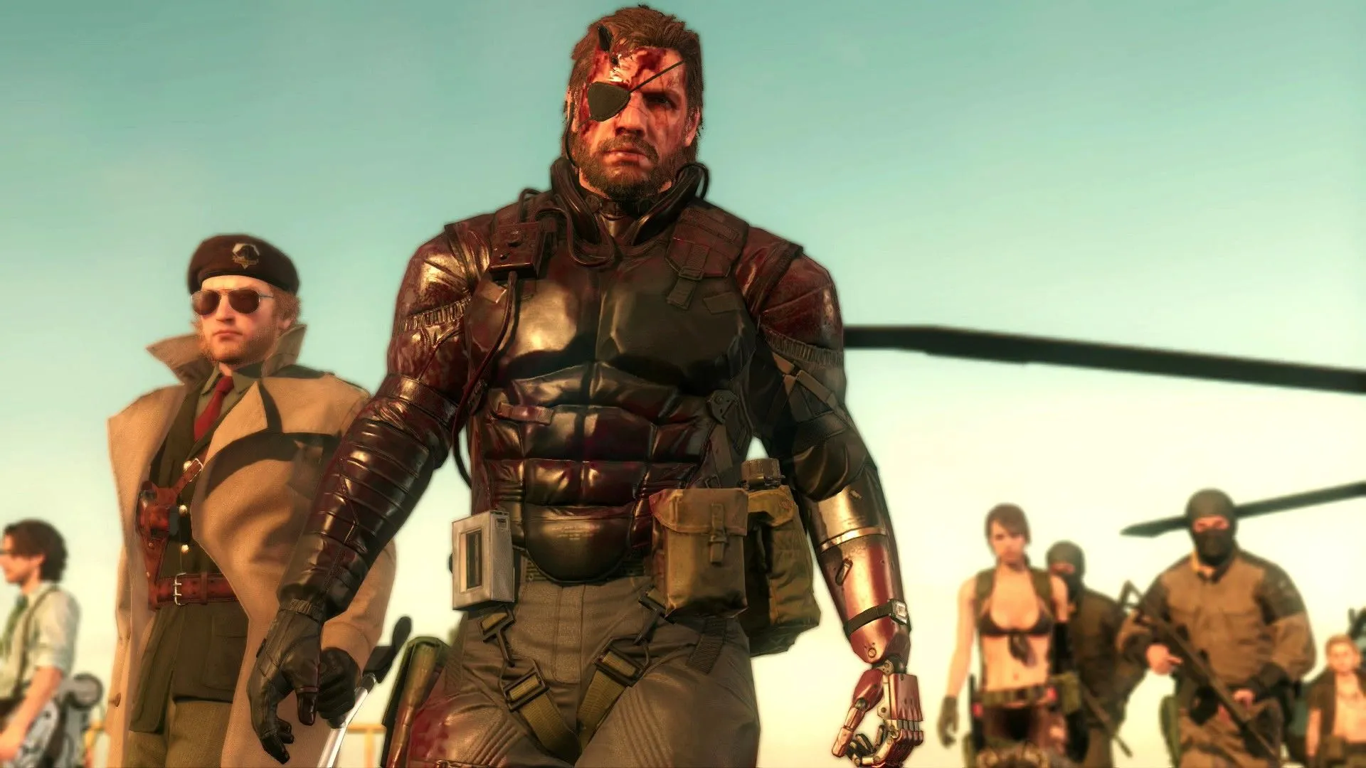 Huey Emmerich, Kazuhira Miller, Venom Snake, Quiet và các binh sĩ khác đang nhìn màn hình trong Metal Gear Solid V Phantom Pain, thể hiện sự phức tạp của cốt truyện chính trị và gián điệp.