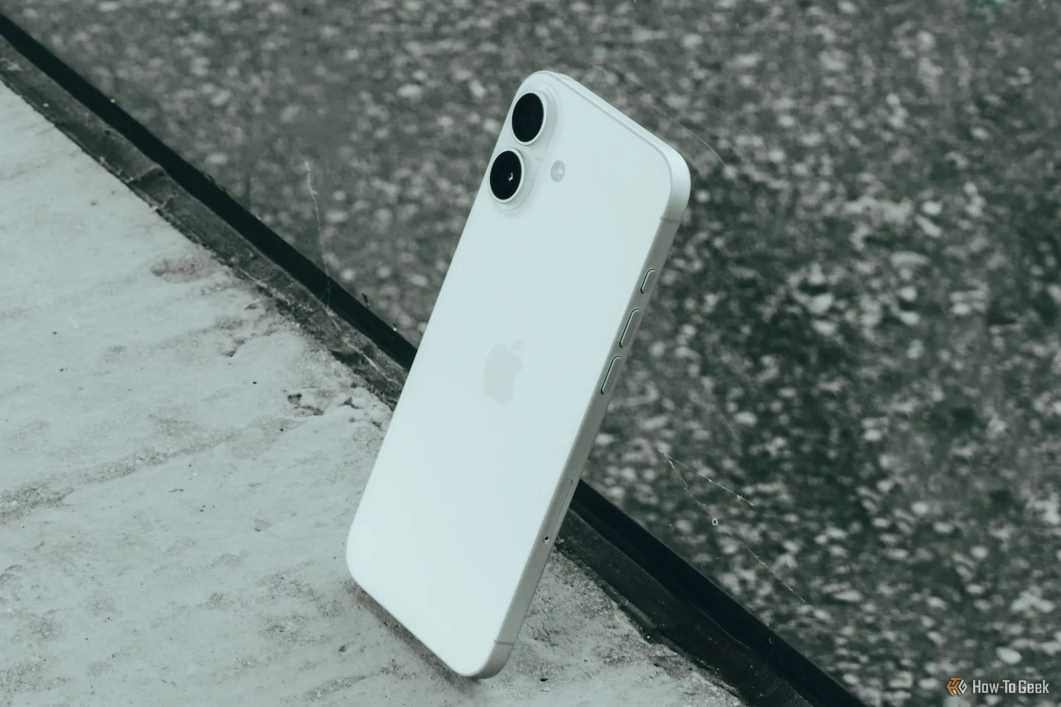 iPhone 16 Plus với màn hình lớn, đặt nghiêng trên bề mặt kính