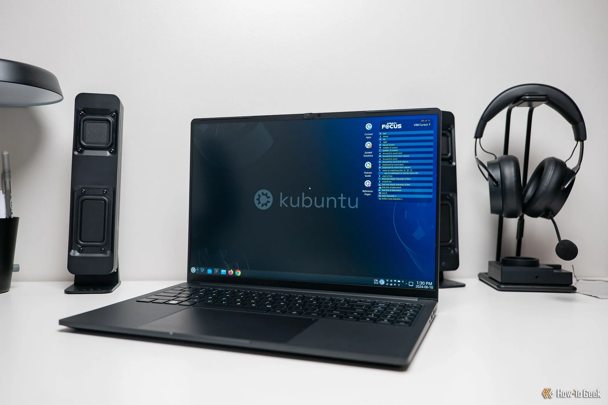 Laptop Kubuntu Focus Ir16 Gen 2 trên bàn làm việc cùng loa và tai nghe, thể hiện môi trường làm việc chuyên nghiệp với máy tính Linux.