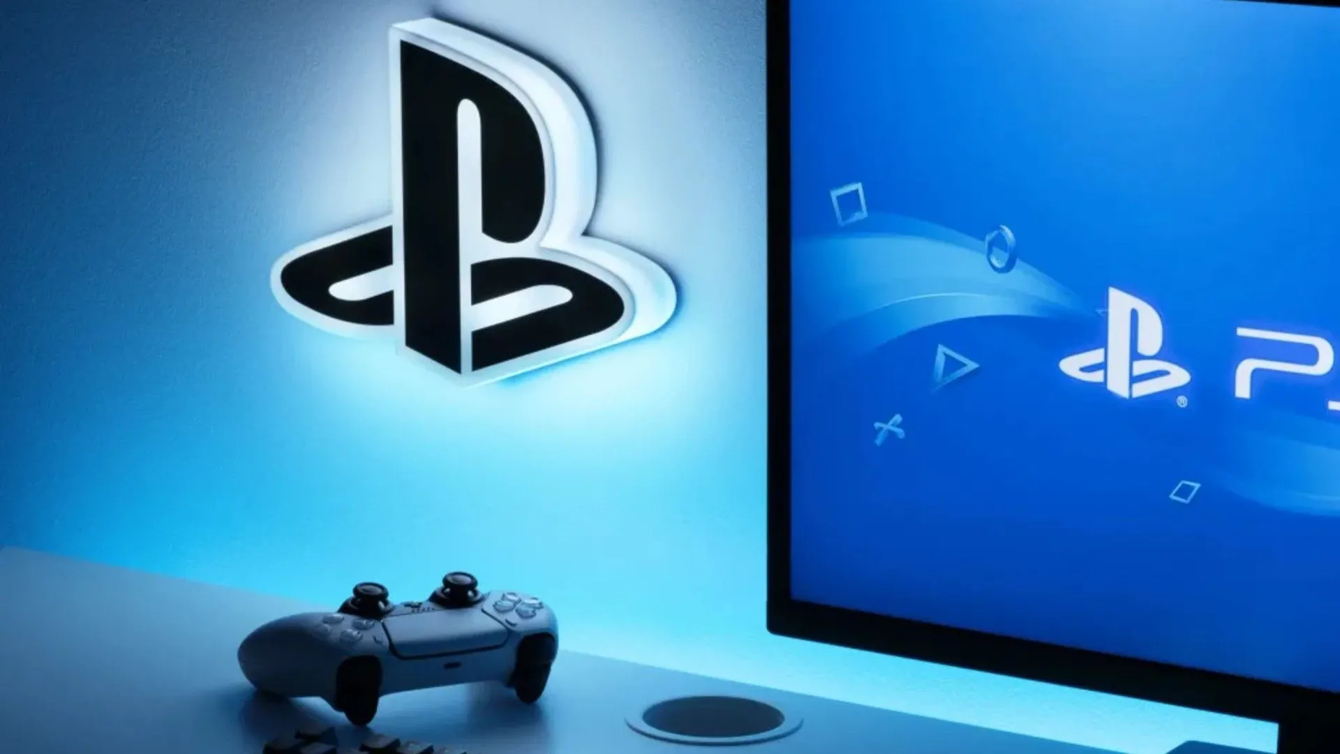 Logo PlayStation trên tường cạnh tay cầm PS5 và màn hình hiển thị logo PS5, thể hiện sự phổ biến của nền tảng này trong ngành game.