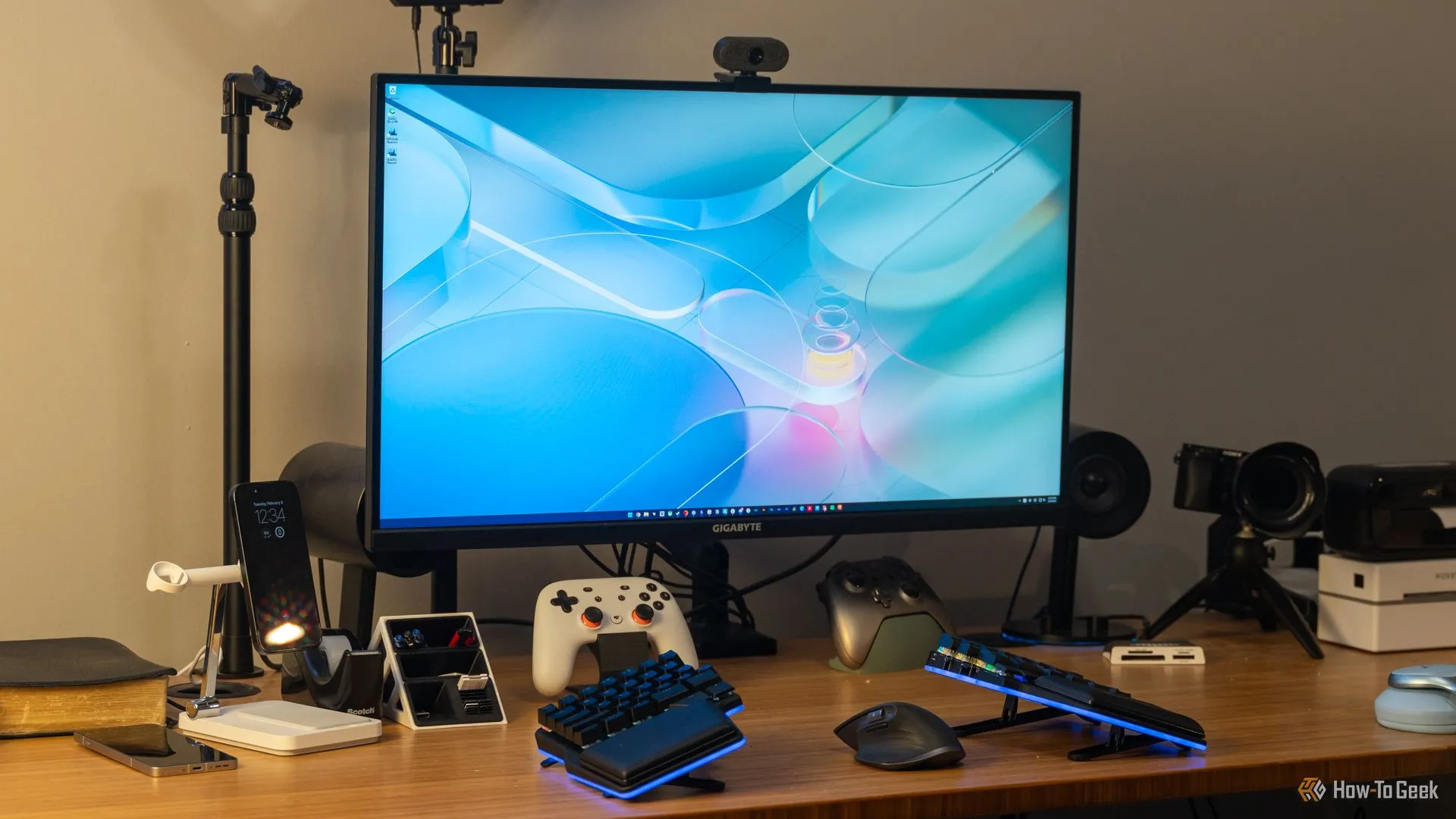 Màn hình gaming 4K GIGABYTE M32U 16:9 trên bàn làm việc, với bàn phím, tay cầm và các phụ kiện khác