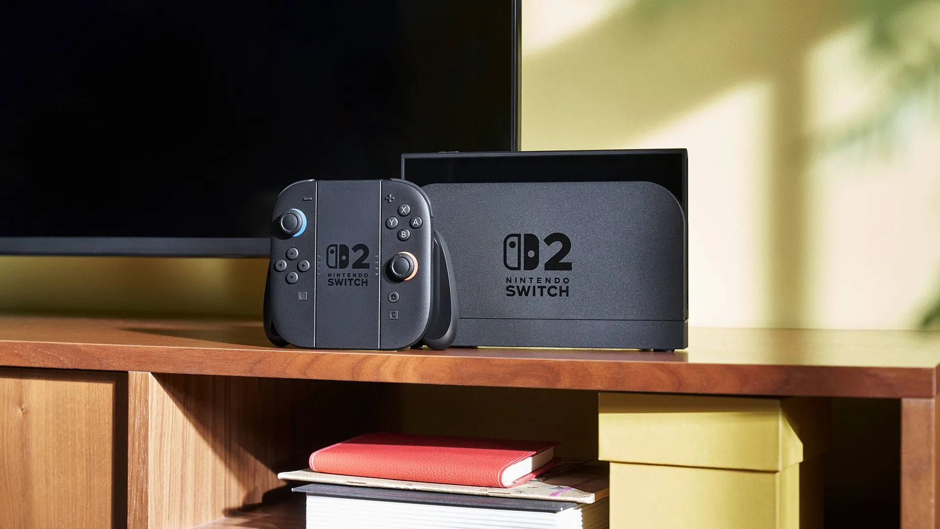 Máy chơi game Nintendo Switch 2 với tay cầm Joy-Cons được gắn vào và đặt trên đế sạc, kết nối với TV
