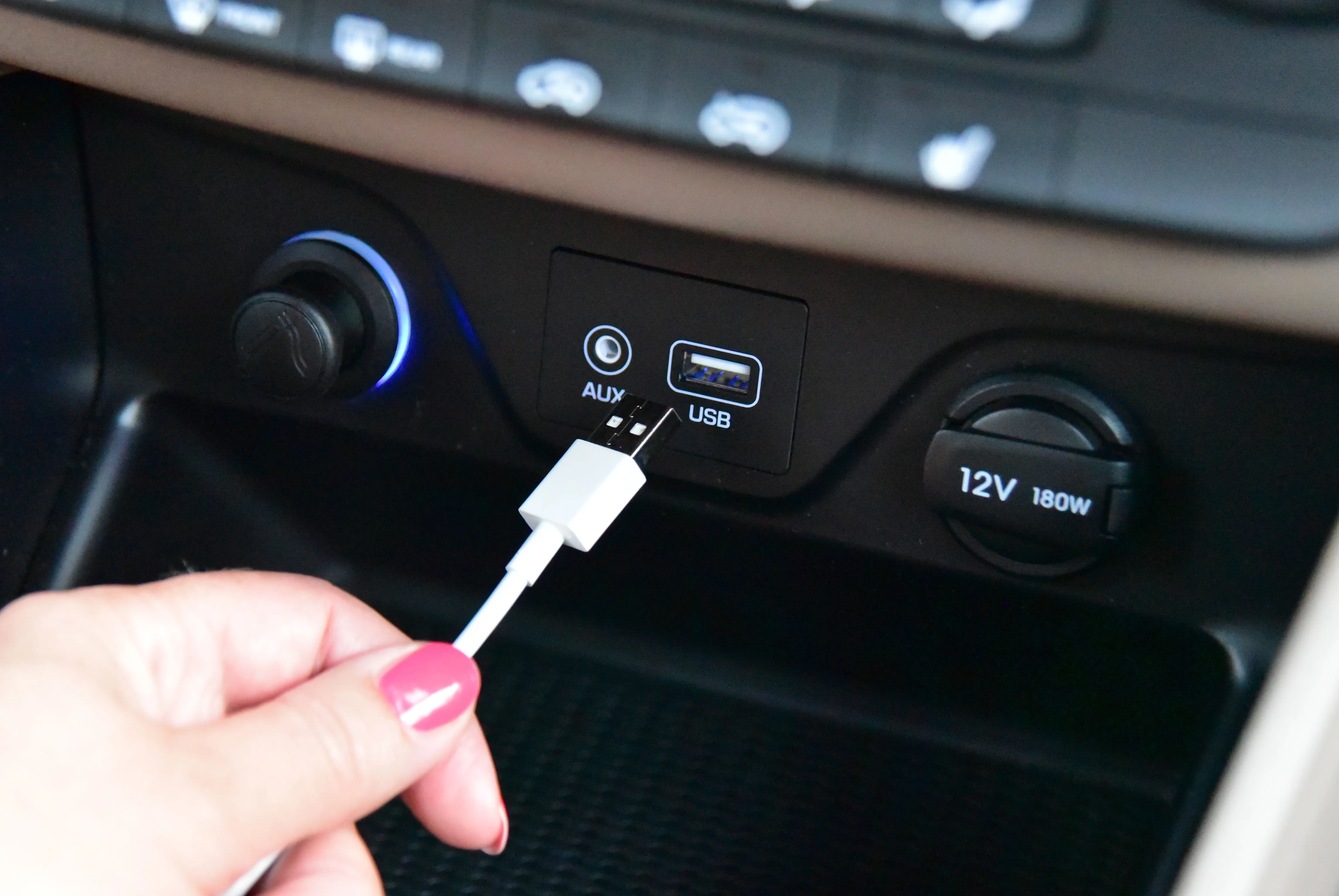 Một bàn tay đang cắm cáp USB-A vào cổng sạc trên bảng điều khiển ô tô, minh họa khó khăn khi cắm sai chiều