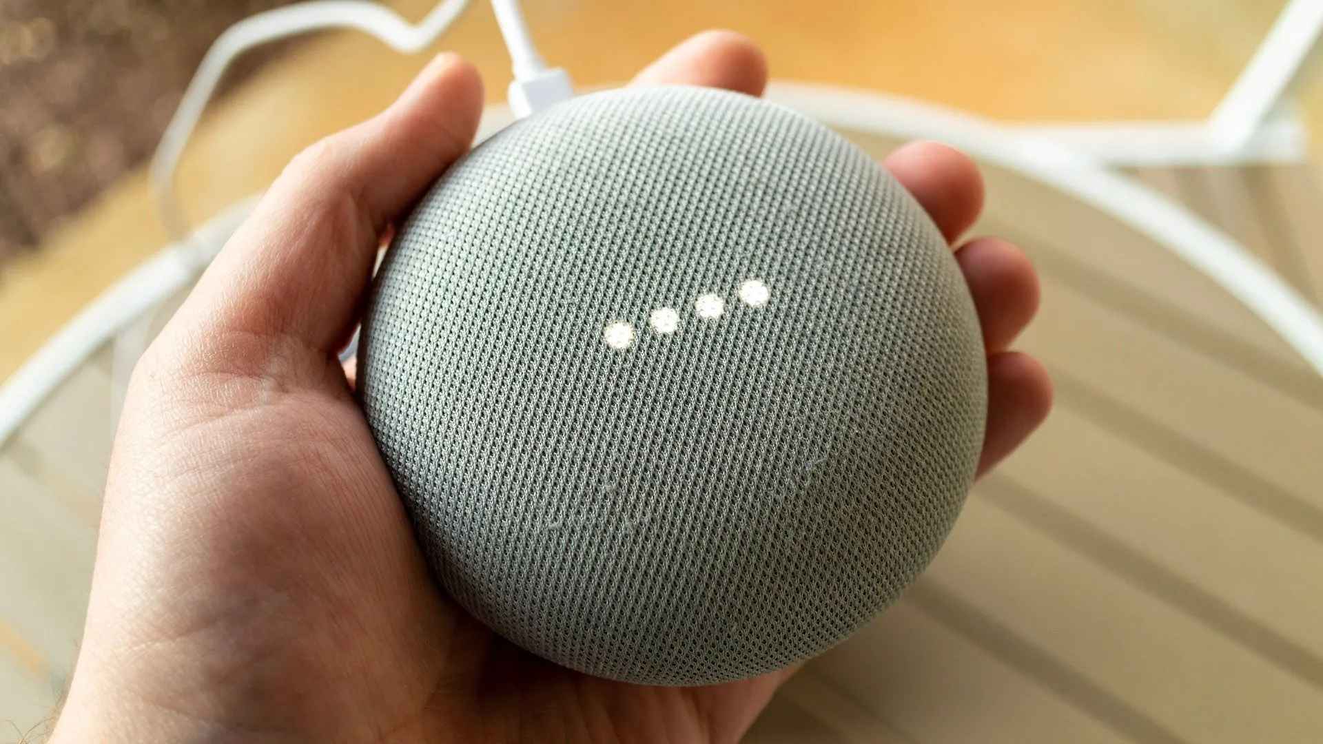 Một bàn tay đang cầm loa thông minh Google Nest, đại diện cho việc điều khiển Home Assistant qua Google Assistant