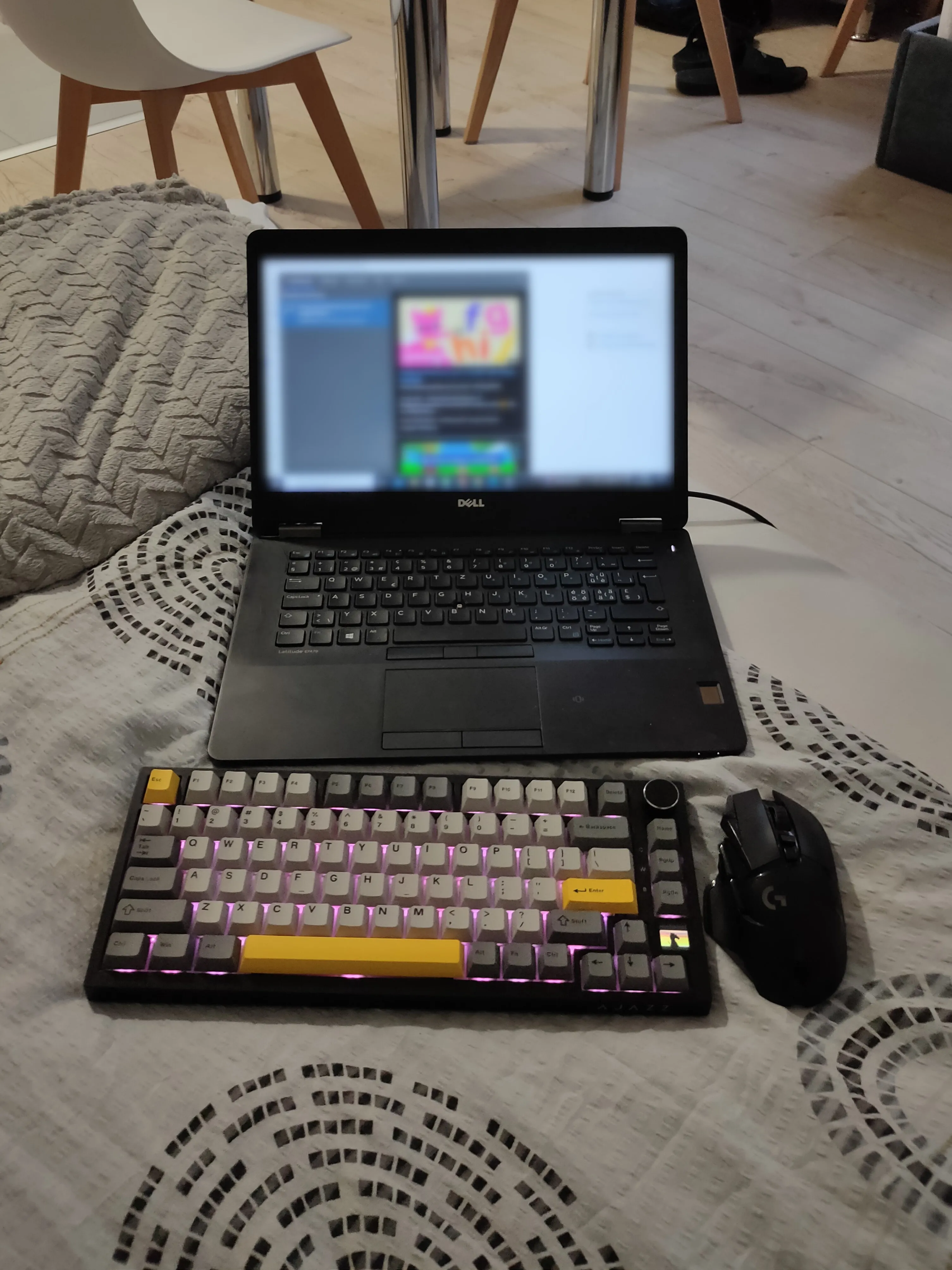 Một chiếc bàn phím và chuột không dây được đặt cạnh một chiếc laptop trên giường, gợi ý về khả năng làm việc di động.