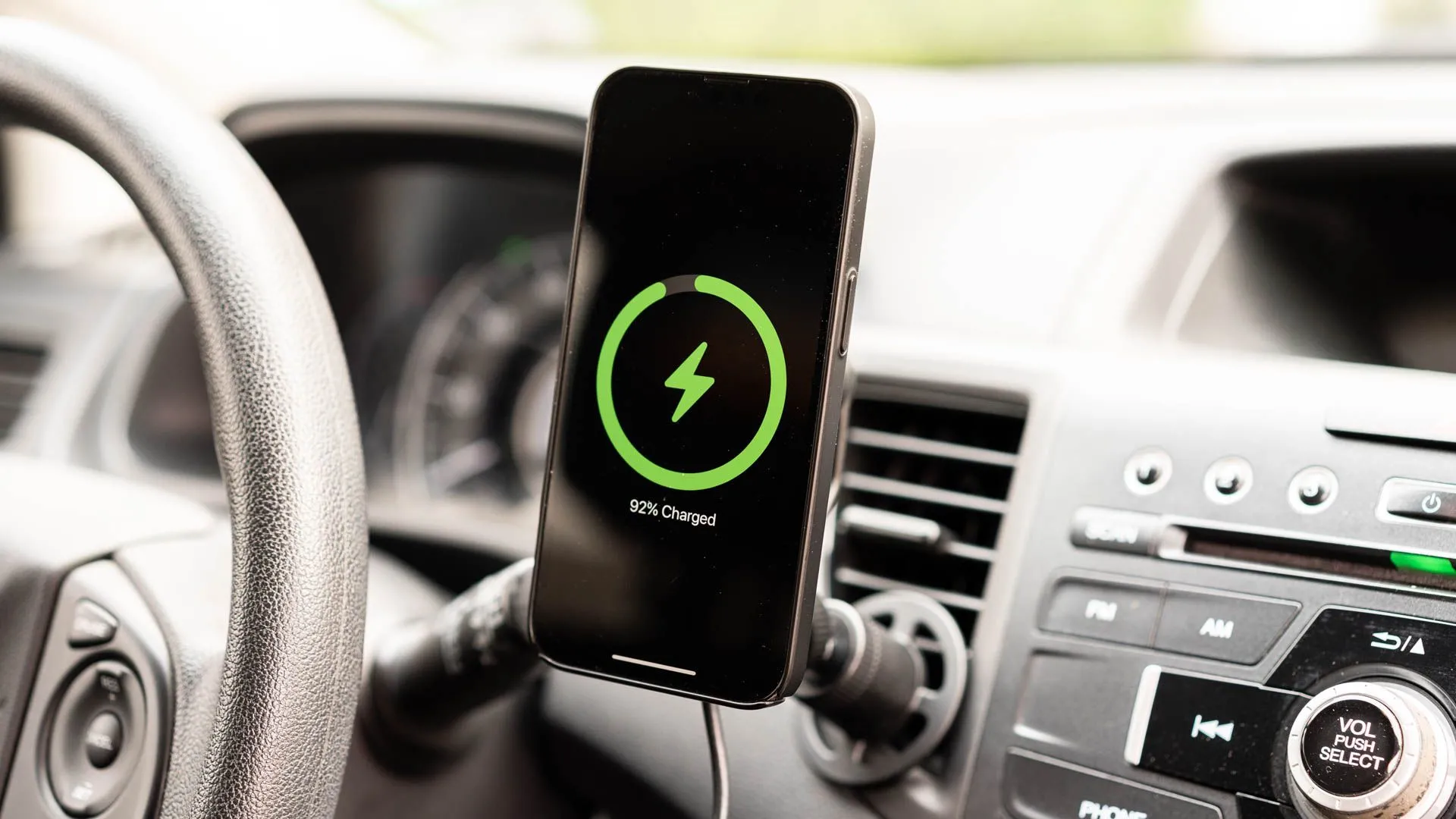 Một chiếc iPhone đang sạc trên giá đỡ sạc không dây mophie gắn lỗ thông hơi với MagSafe