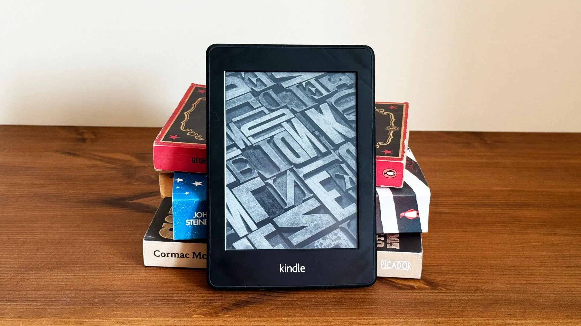 Một chiếc máy đọc sách Kindle đặt trước chồng sách giấy, minh họa khả năng đọc không quảng cáo