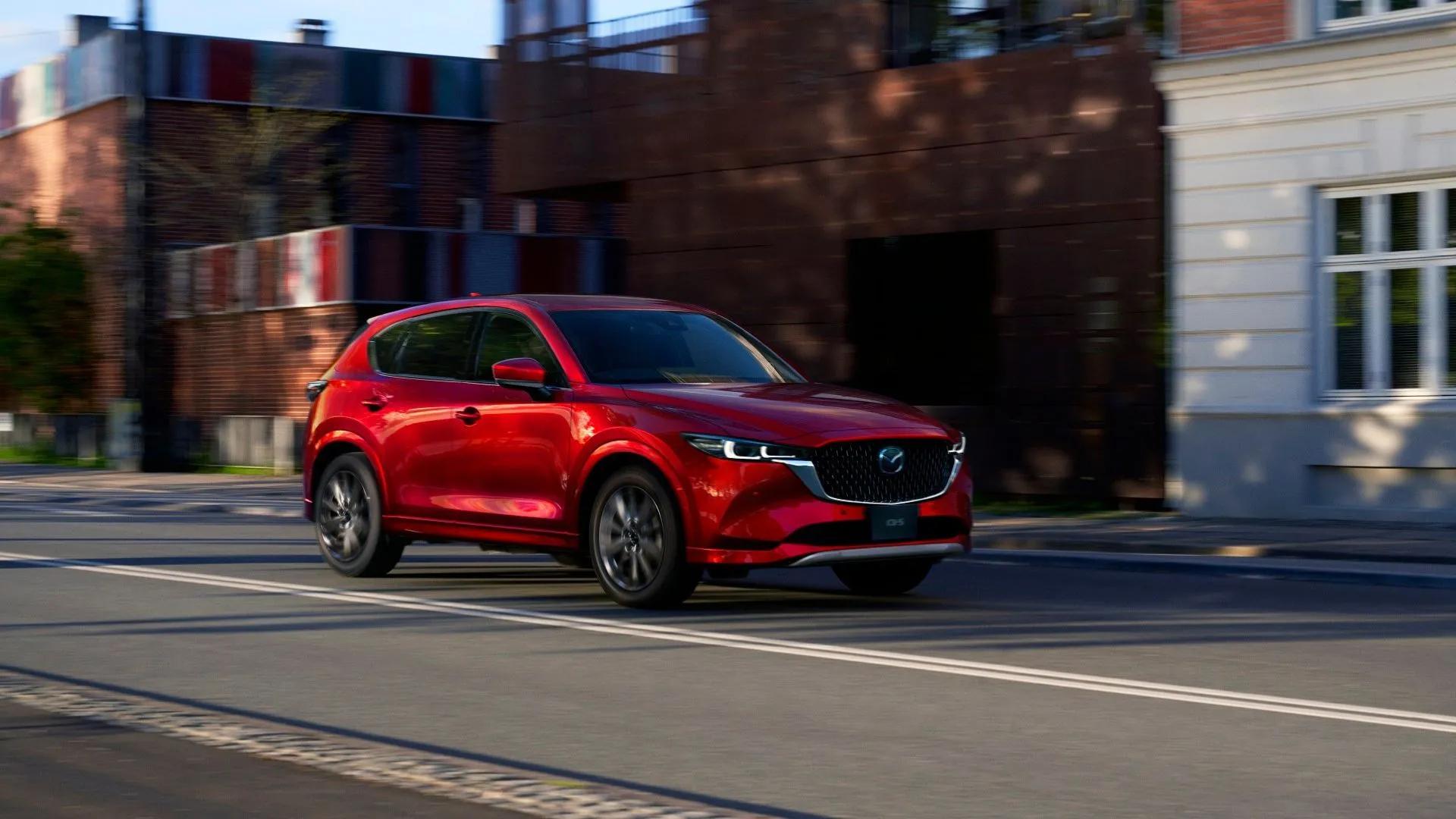 Một chiếc xe SUV Mazda CX-5 phiên bản mới màu đỏ rực rỡ đang di chuyển trên đường.