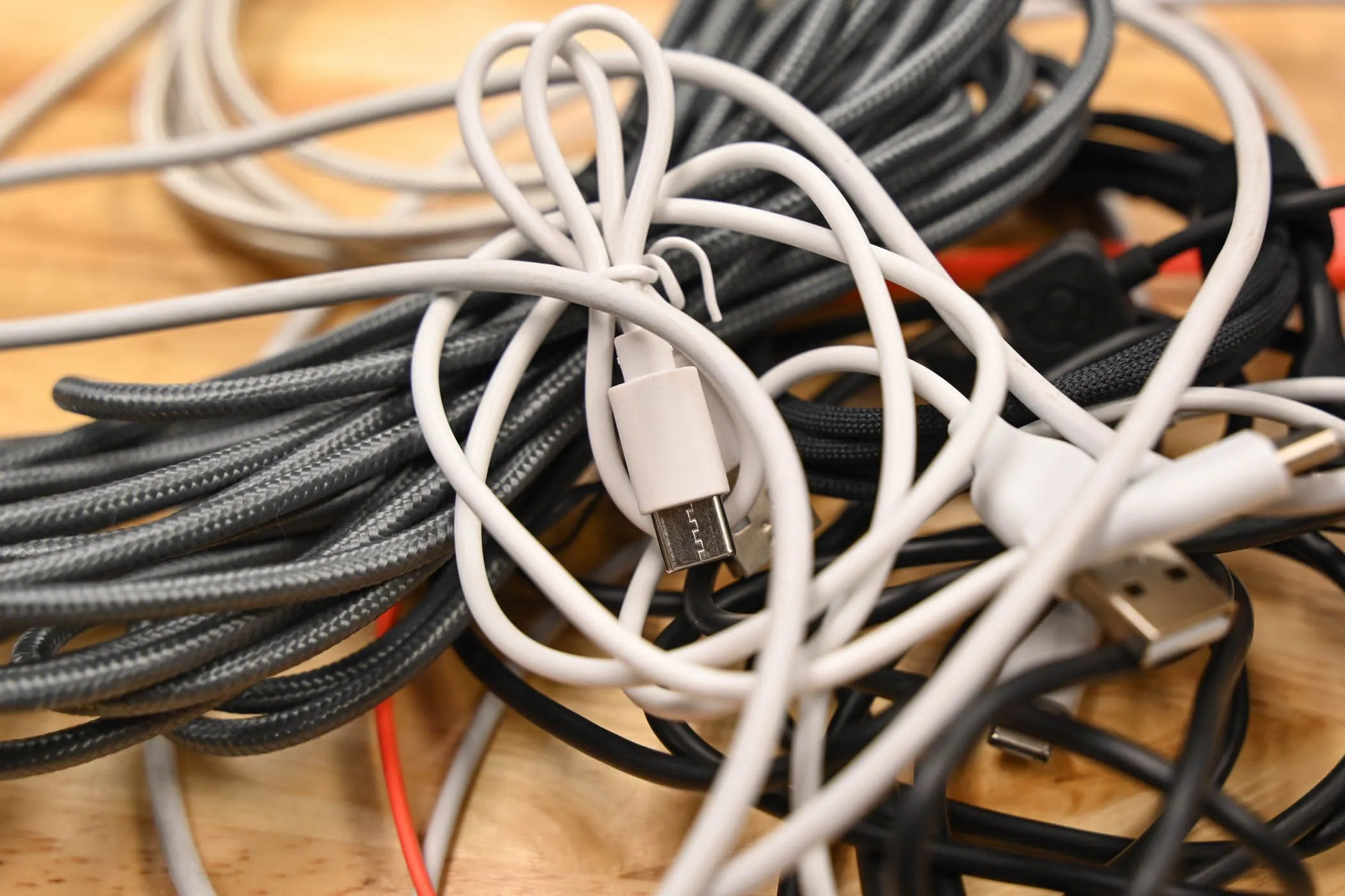 Một đống cáp USB cũ nằm lộn xộn trên mặt bàn gỗ, minh họa cho ngăn kéo cáp đã tích trữ nhiều năm.