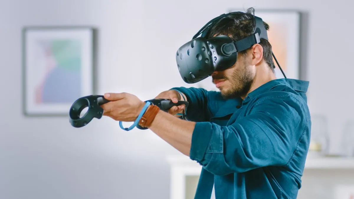 Một người đàn ông trải nghiệm thực tế ảo (VR) với kính headset và tay cầm điều khiển, minh họa công nghệ game là nền tảng của VR/AR.