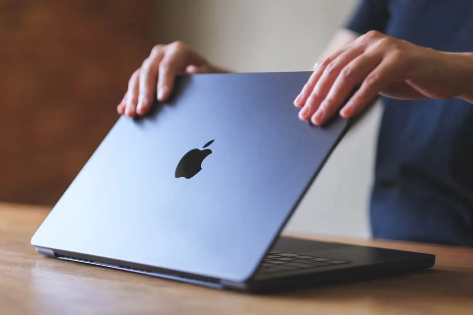 Một người đang mở laptop MacBook trên bàn làm việc.