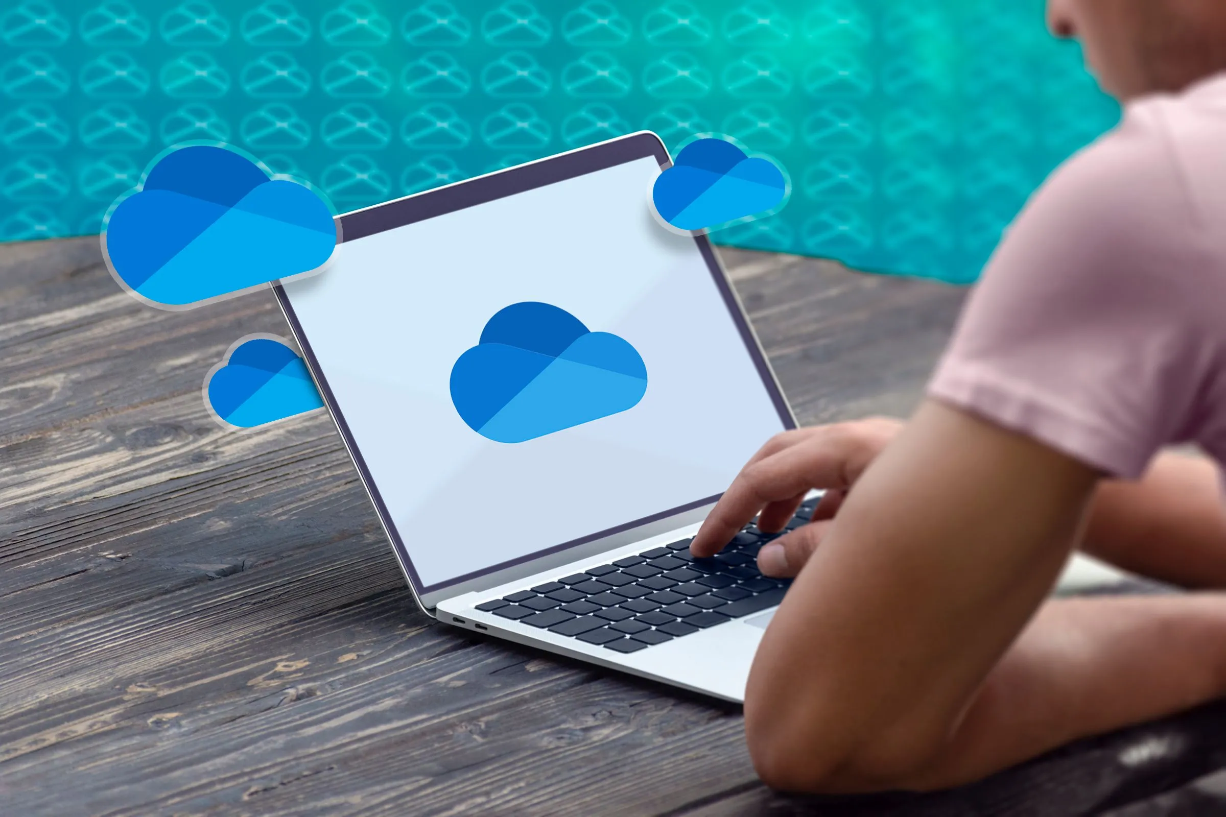Một người đang sử dụng máy tính xách tay với logo OneDrive hiển thị trên màn hình, tượng trưng cho việc sử dụng dịch vụ này