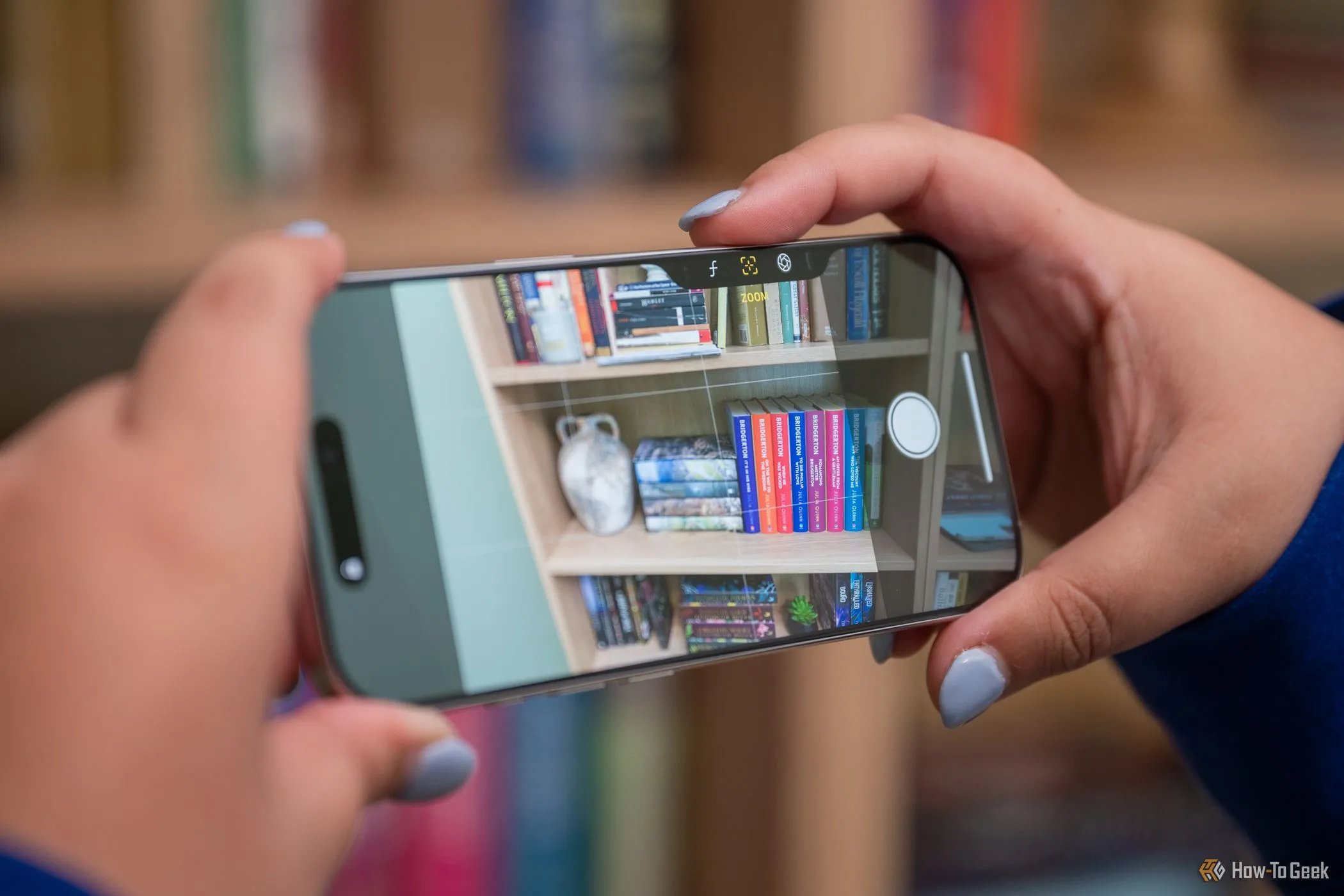 Người đang chụp ảnh bằng nút Camera Control trên iPhone 16 Pro theo chiều ngang