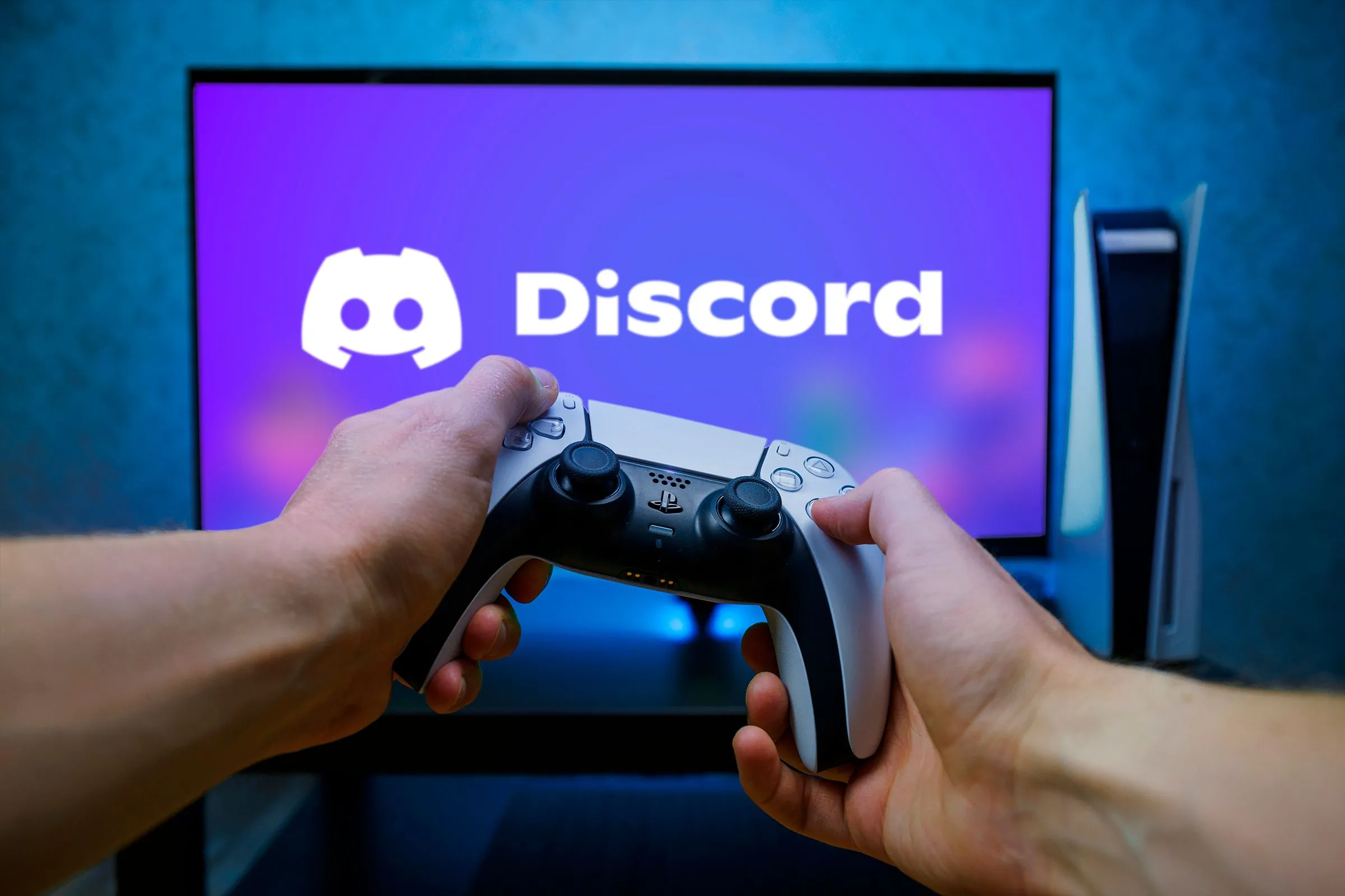 Người dùng cầm bộ điều khiển PS5 với logo Discord trên màn hình TV, thể hiện cộng đồng game thủ trên Discord