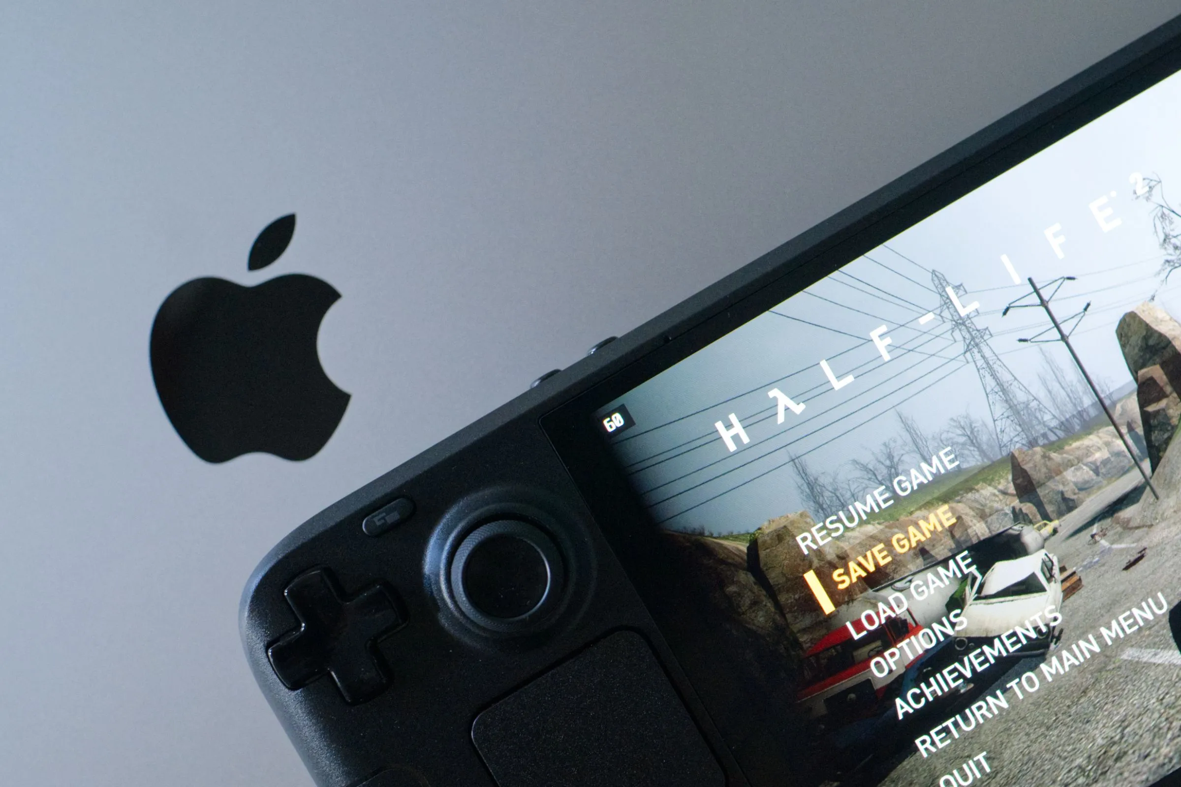 Người dùng chơi Half-Life 2 trên Steam Deck OLED đặt trên MacBook Pro, thể hiện trải nghiệm game tiện lợi.
