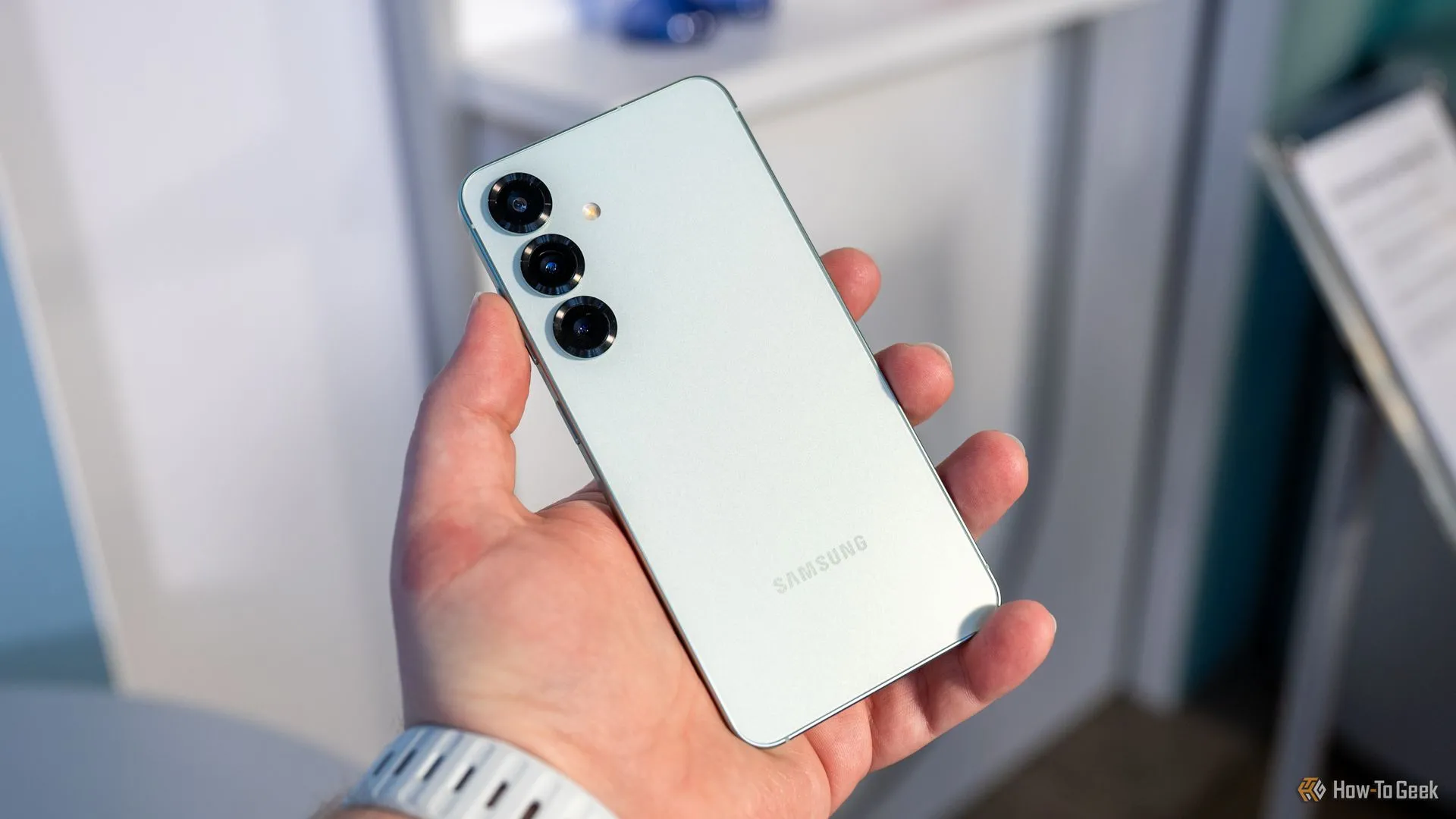 Người dùng đang cầm Samsung Galaxy S25 và nhìn vào các camera phía sau.