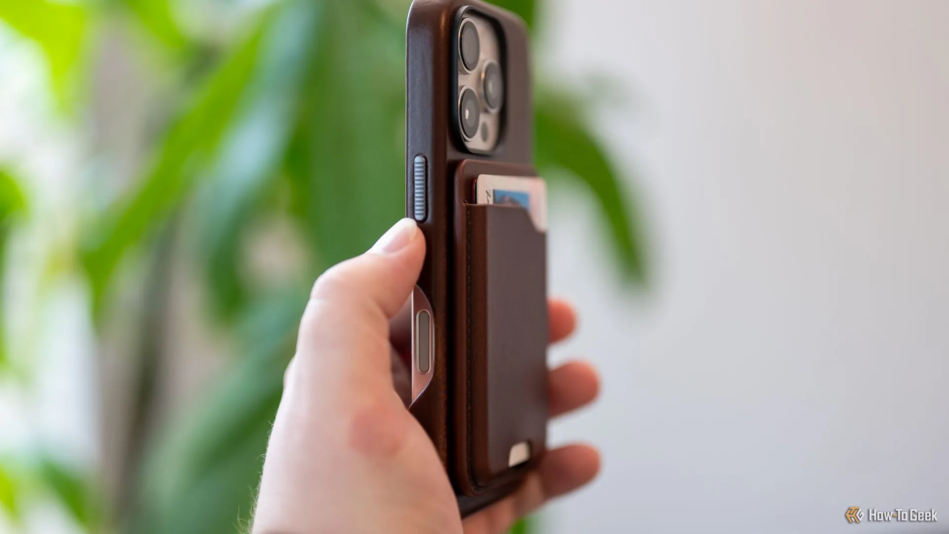 Người dùng đang cầm ví da Nomad Leather Mag Wallet gắn vào mặt lưng iPhone