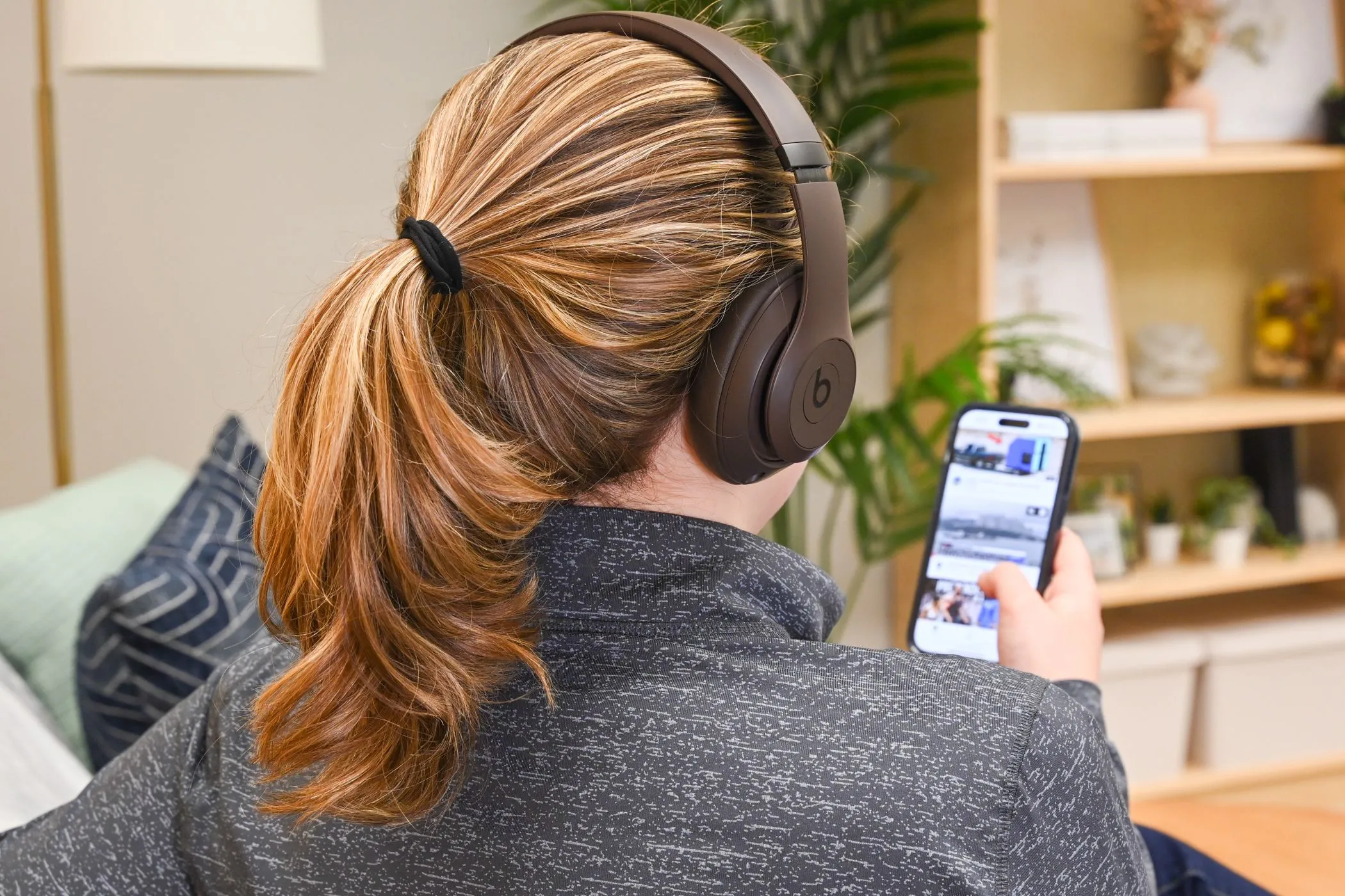 Người dùng đeo tai nghe Beats Studio Pro đang thưởng thức video ngắn trên iPhone, minh họa cho trải nghiệm xem nội dung trên mạng xã hội.