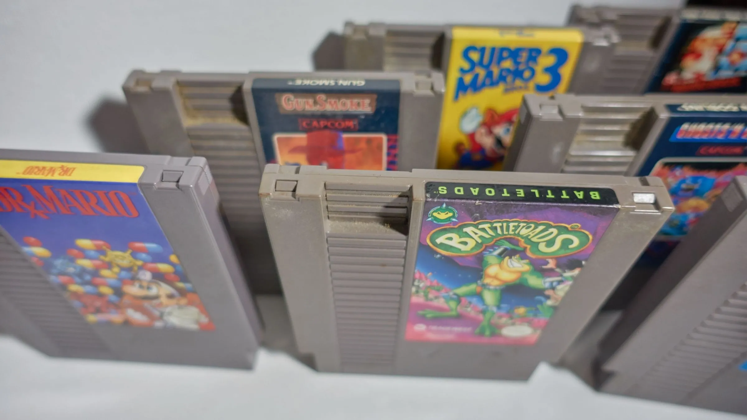 Nhiều băng game NES màu xám xếp cạnh nhau, trong đó có băng game Battletoads nổi tiếng khó nhằn.